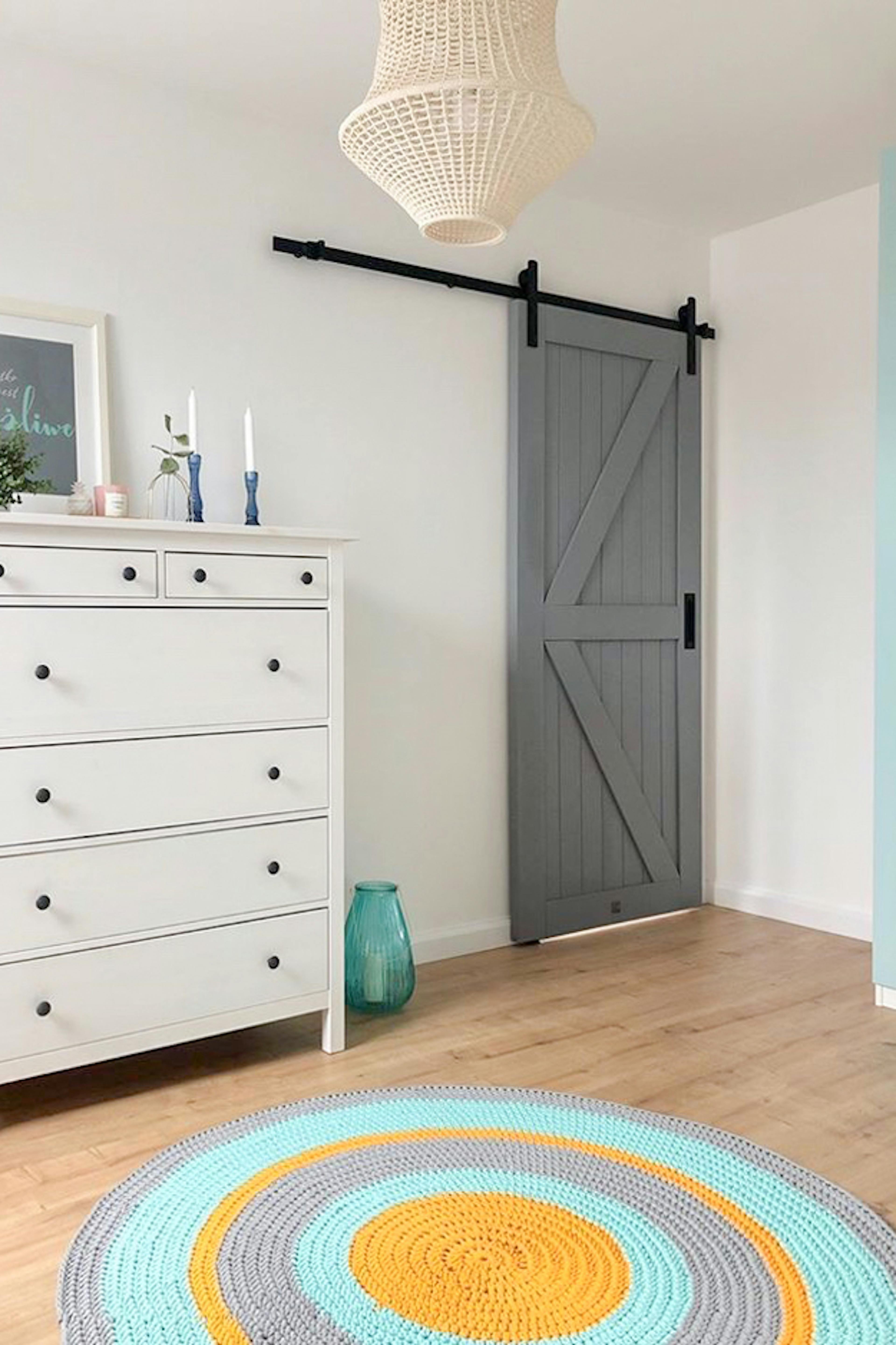commode blanche, moquette colorée et portes coulissantes grises sur fond de murs blancs
