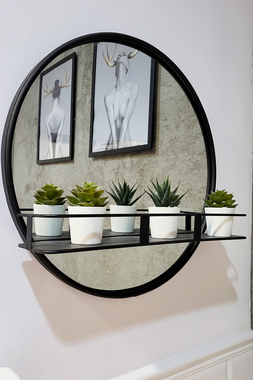 okrągłe lustro w czarnej ramce, z małą półką
