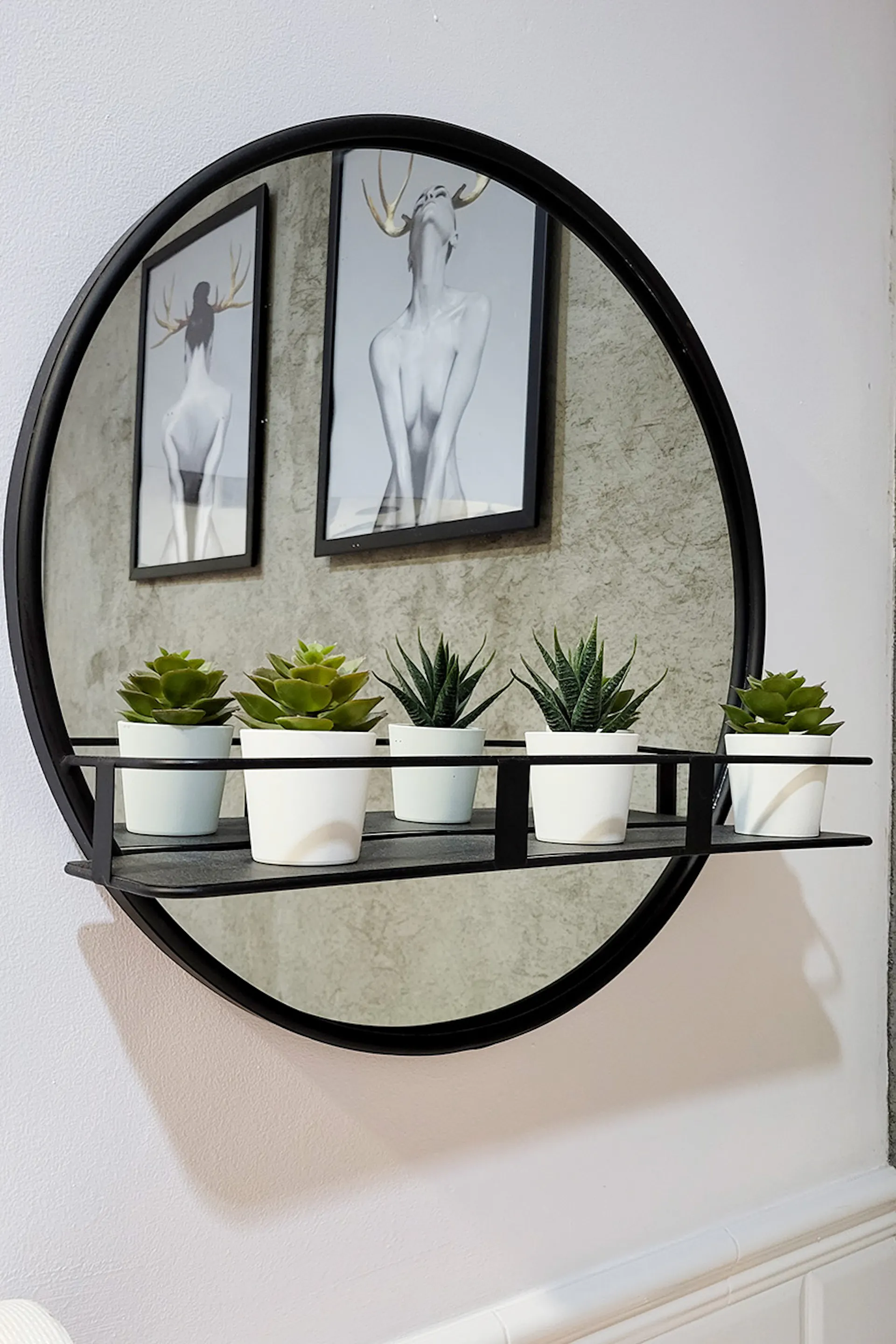 okrągłe lustro w czarnej ramce, z małą półką
