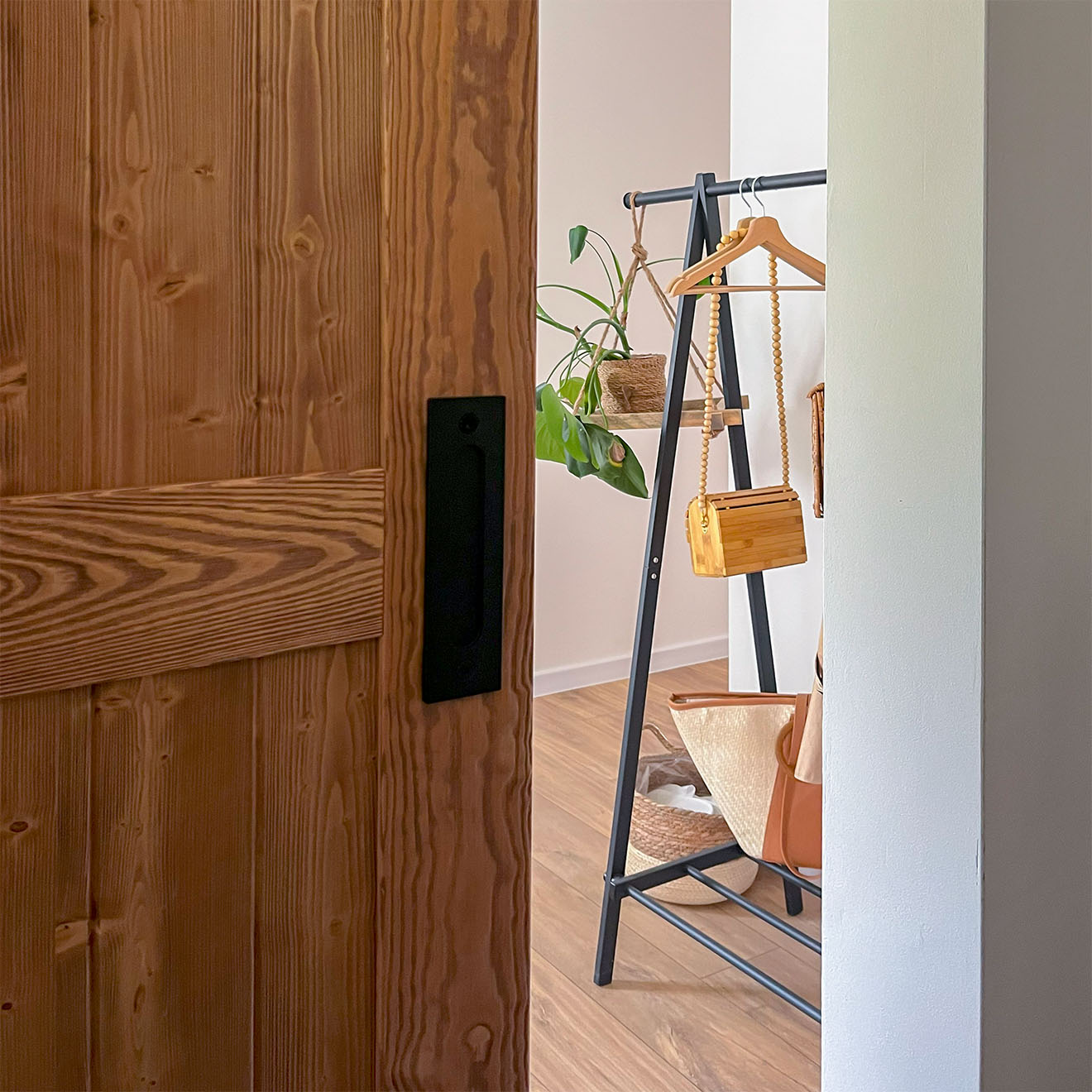 uchylone drzwi drewniane ukazujące fragment przedpokoju ze stojakiem na ubrania
