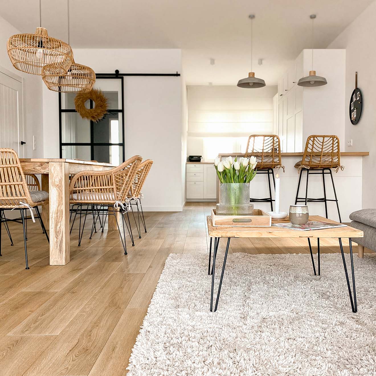 Wohnzimmer mit weißen Wänden und Naturholz-, Rattan- und Korbmöbeln