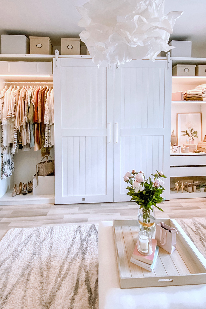 Pendelleuchte Papier Lampenschirm, weiße Schiebetüren für den Kleiderschrank, barn door im begehbarer Kleiderschrank, ein System aus weißen Kleiderschränken und Regalen im Ankleidezimmer, großer Kleiderschrank in Weiß, weiße Türen auf einem weißen Schiebesystem