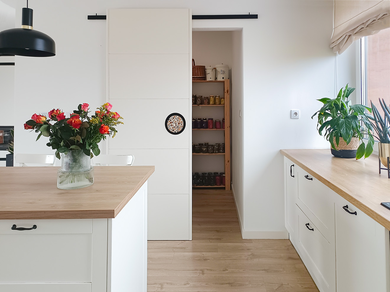 otwarte drzwi przesuwne do spiżarni w białej kuchni