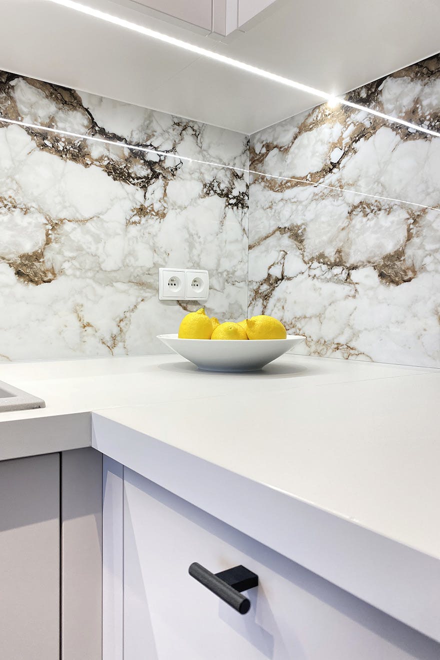 Fliesen mit Steinmotiv über der Küchenarbeitsplatte, weiße Küchenmöbel, modernes Apartment