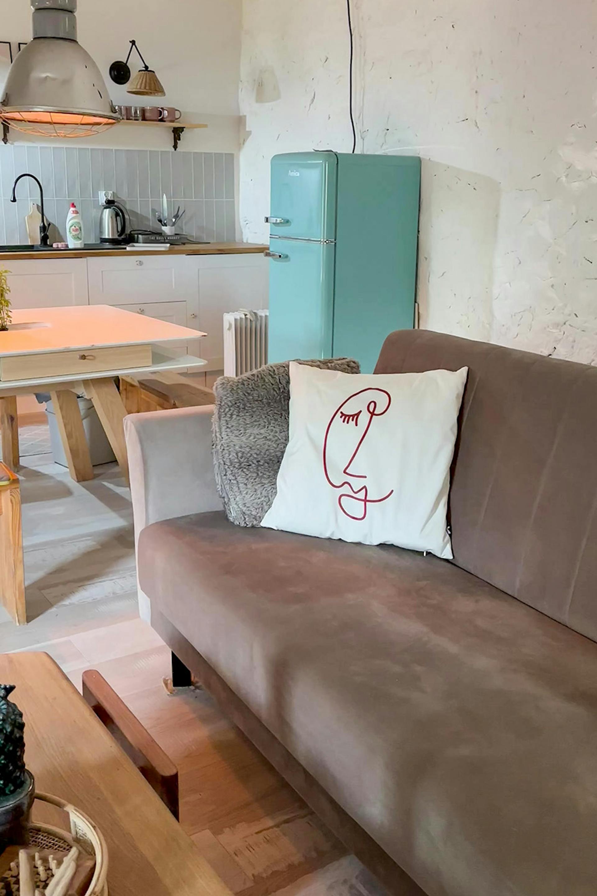 brązowa sofa w salonie i niebieska lodówka w kuchni w aranżacji wnętrza w stylu wiejskim