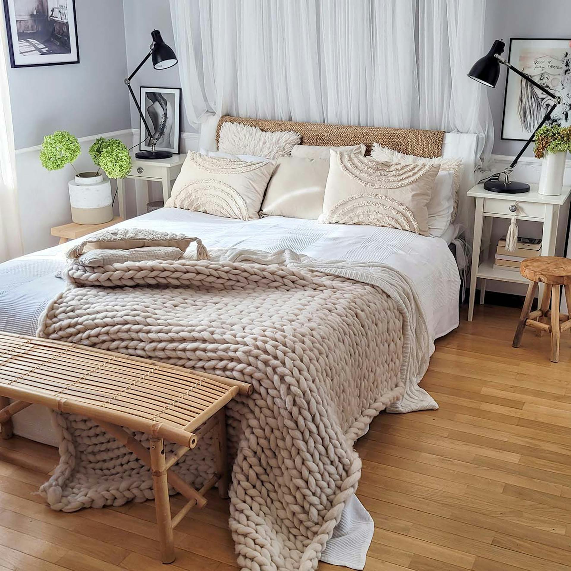 ein Doppelbett mit weißer Bettwäsche, einer dick gewebten Decke und dekorativen Kissen