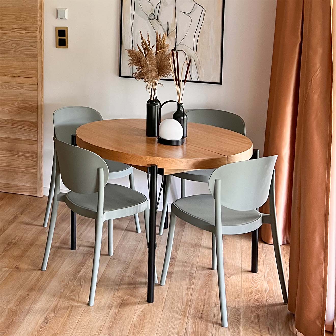 Sage-Stühle stehen um einen runden Tisch mit Holzplatte und Metallbeinen