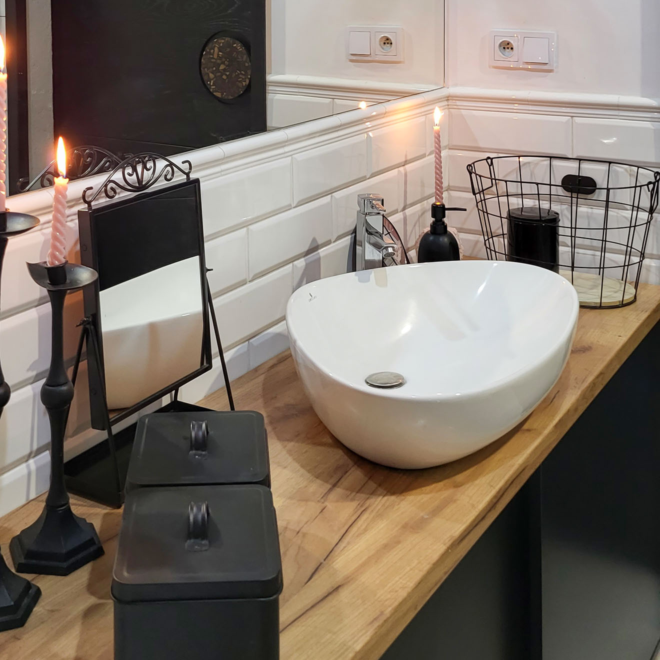 czarne akcesoria i biała umywalka na drewnianym blacie w łazience