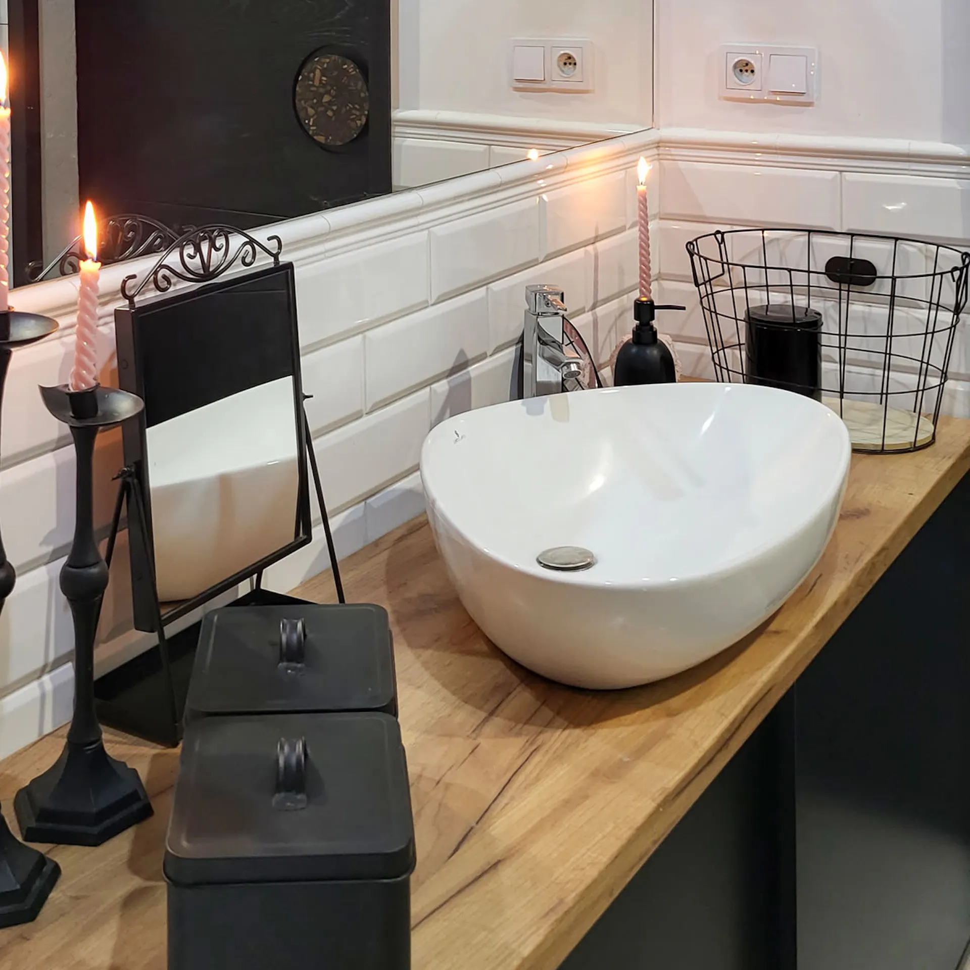 czarne akcesoria i biała umywalka na drewnianym blacie w łazience