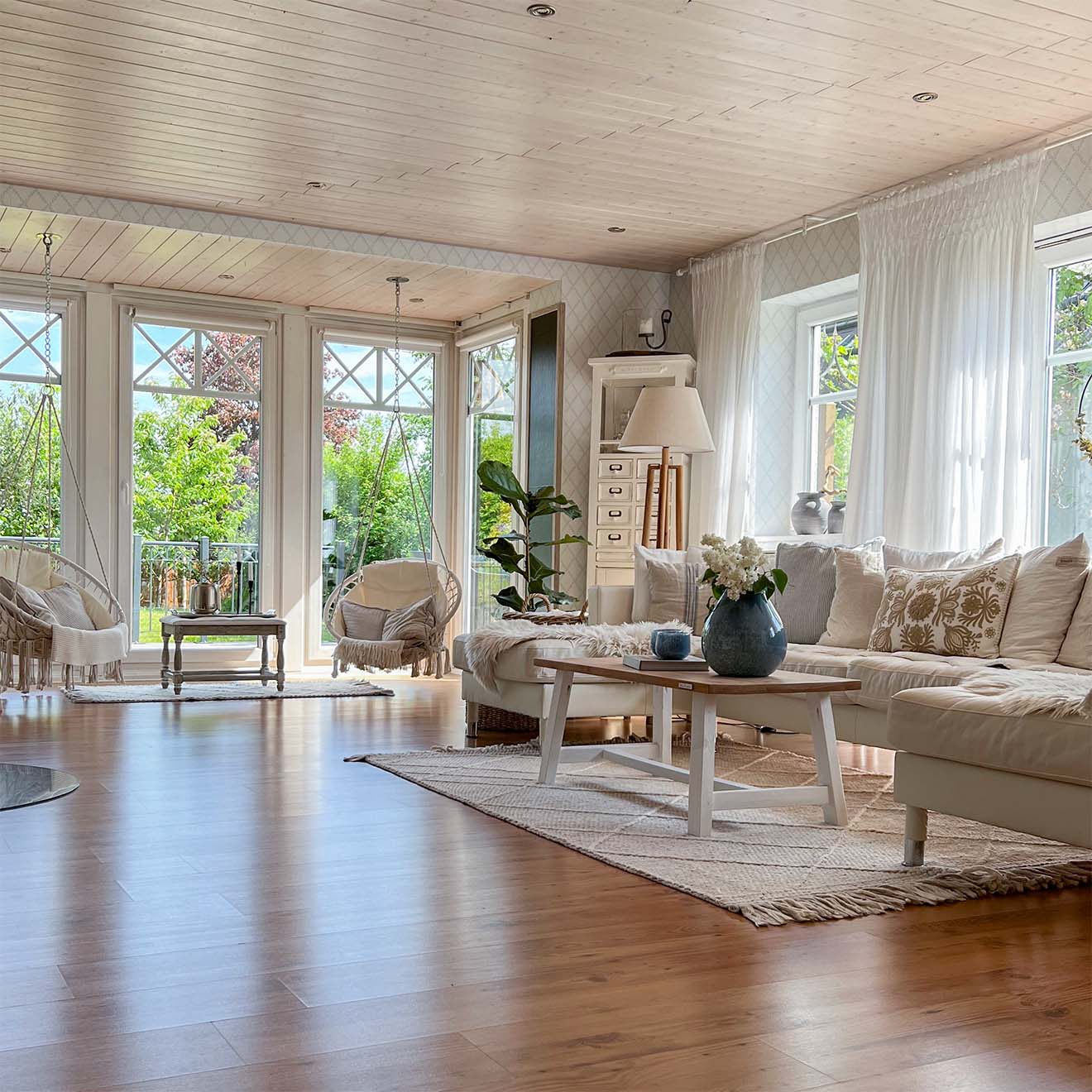 ein geräumiges Wohnzimmer mit Holzboden, einem hellen Sofa und großen Fenstern