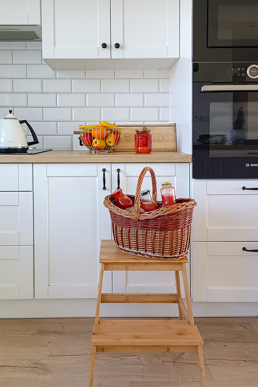 Holzboden, weiße Möbel und weiße Fliesen in der Küche