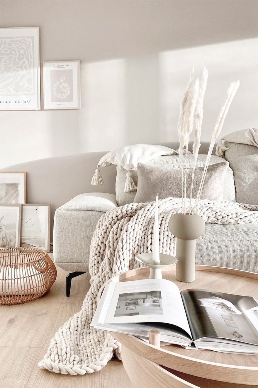 Wohnzimmer in hellen Beigetönen, Wohnzimmer im nordischen Stil, Dekorationen auf dem Couchtisch im Wohnzimmer, beiges Sofa neben einer hellen Wand