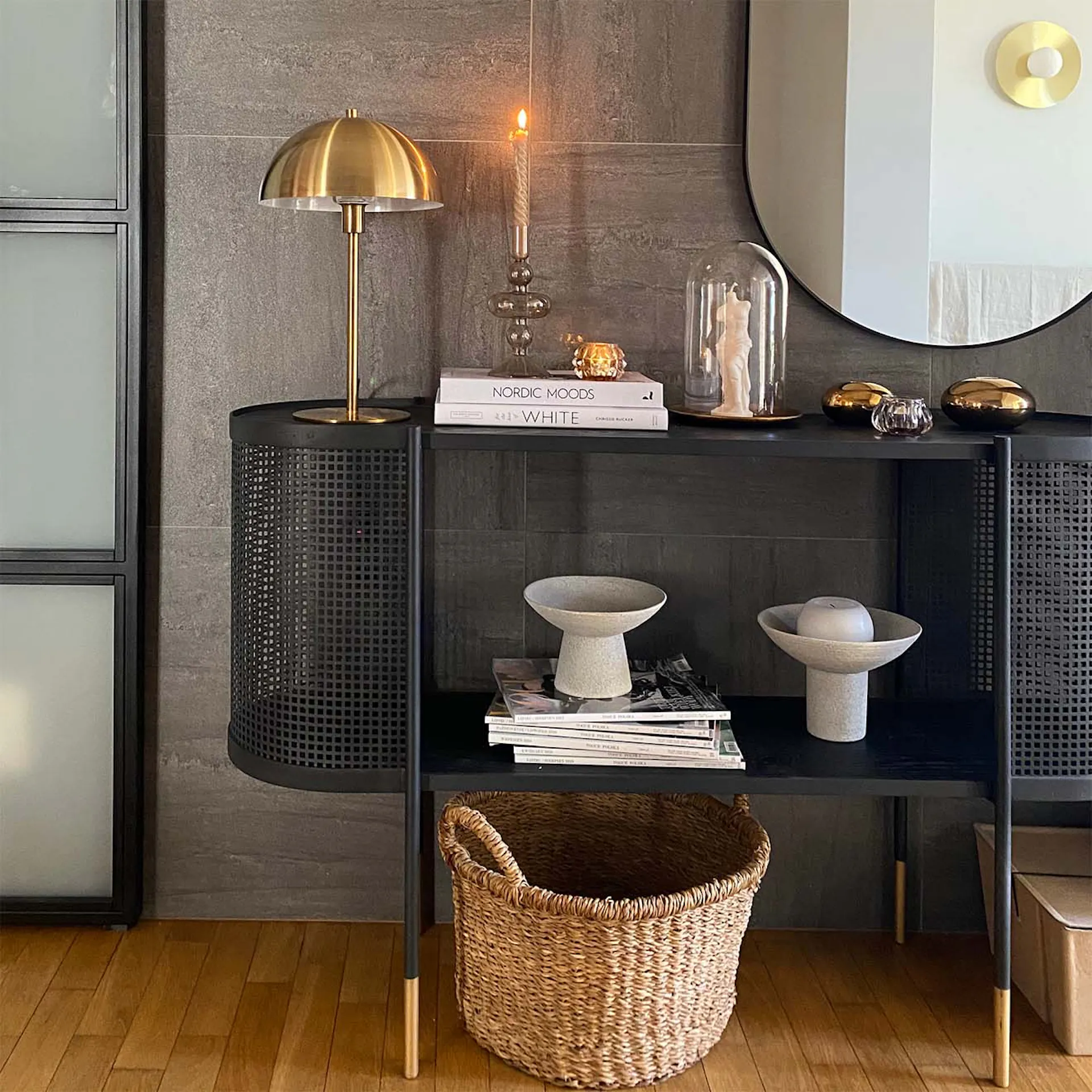 Schwarze durchbrochene Konsole in der Halle, Graphitfliesen an der Wand, goldene Lampe auf der schwarzen Konsole, minimalistische Dekorationen auf der Konsole