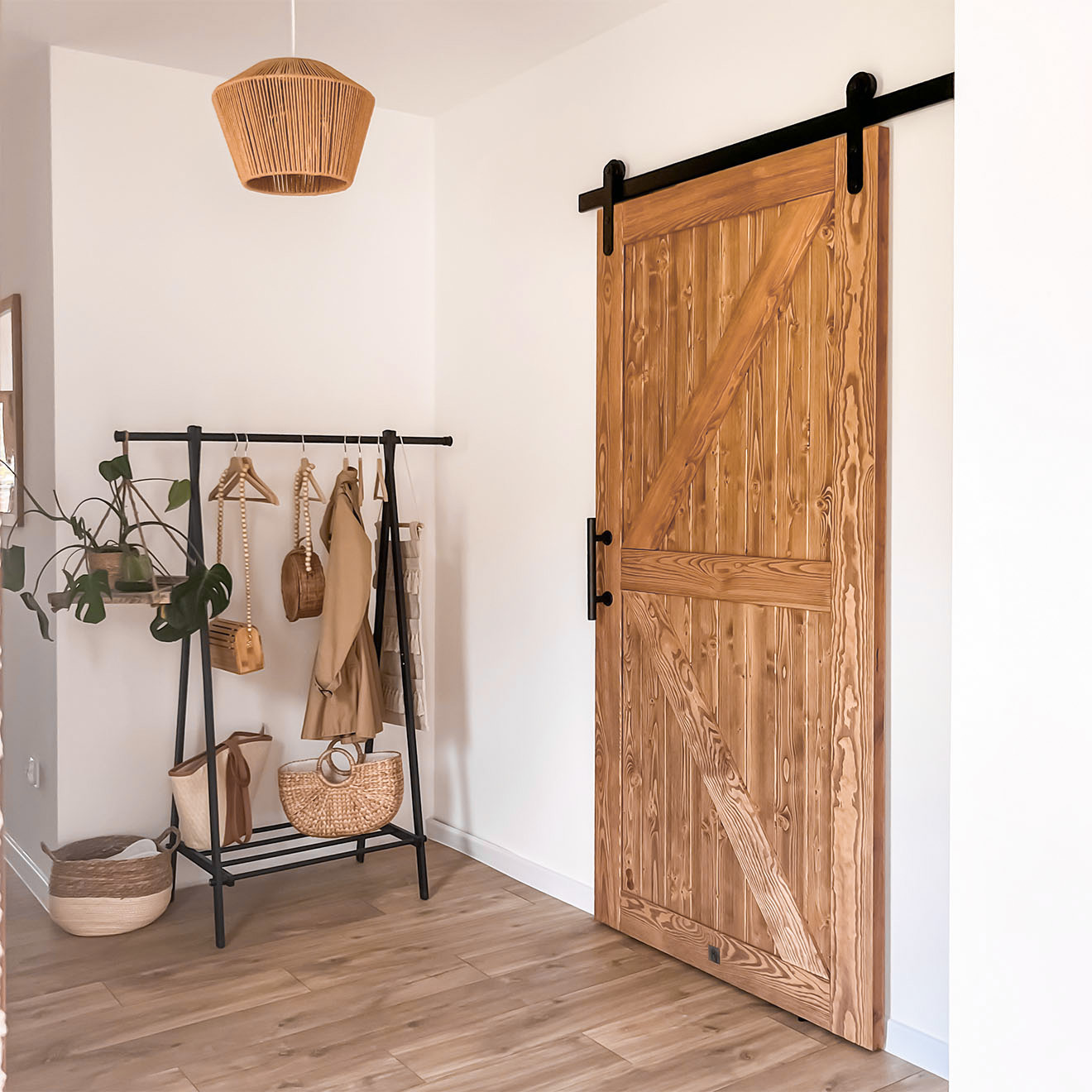 metalowy stojak w wieszakami na ubrania obok drzwi przesuwnych w przedpokoju