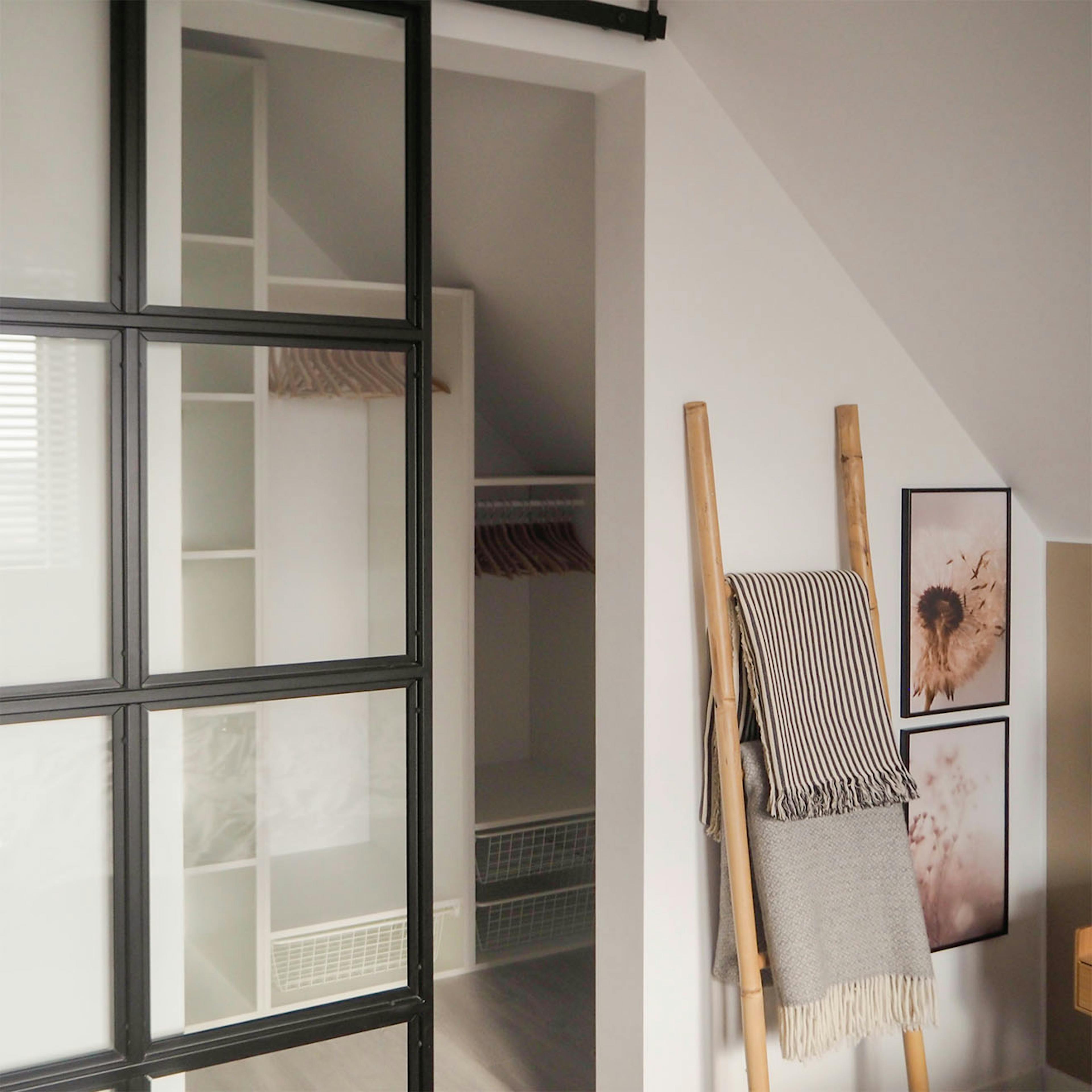 Loft-Stil Tür mit Glas in einem Metallrahmen, der den Ankleidezimmer in einem kleinen Schlafzimmer im Dachgeschoss schließt