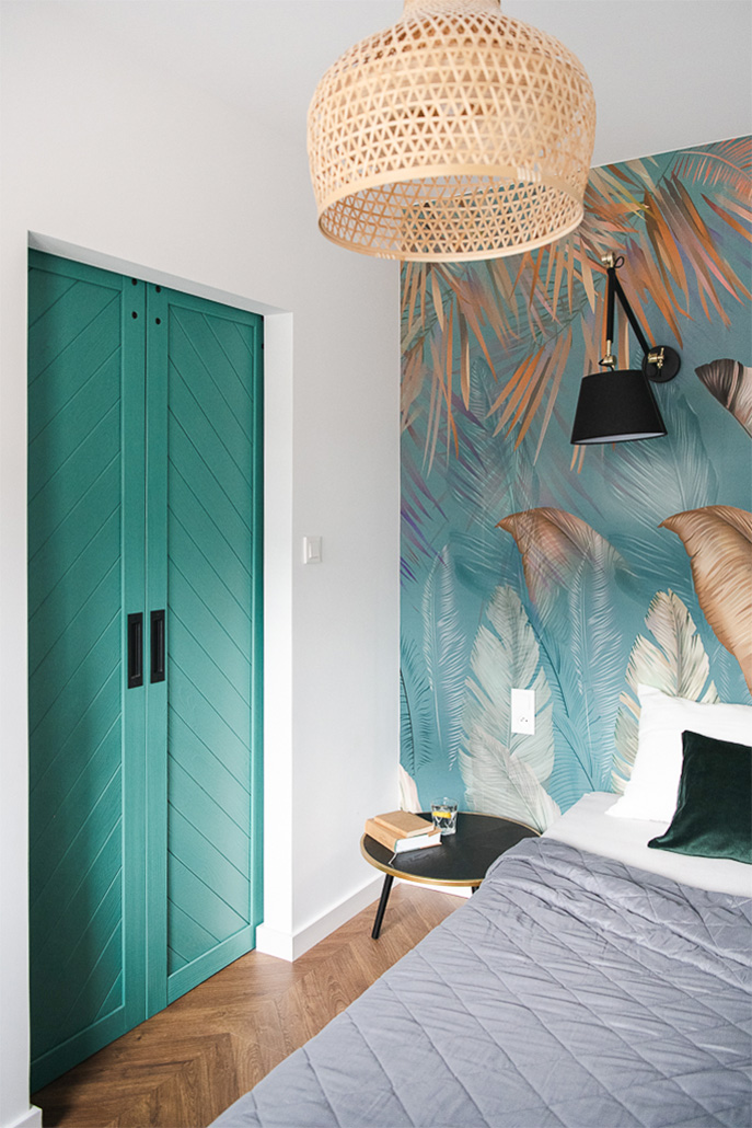 Schlafzimmer mit türkisfarbenen Doppeltüren und dekorativer Tapete