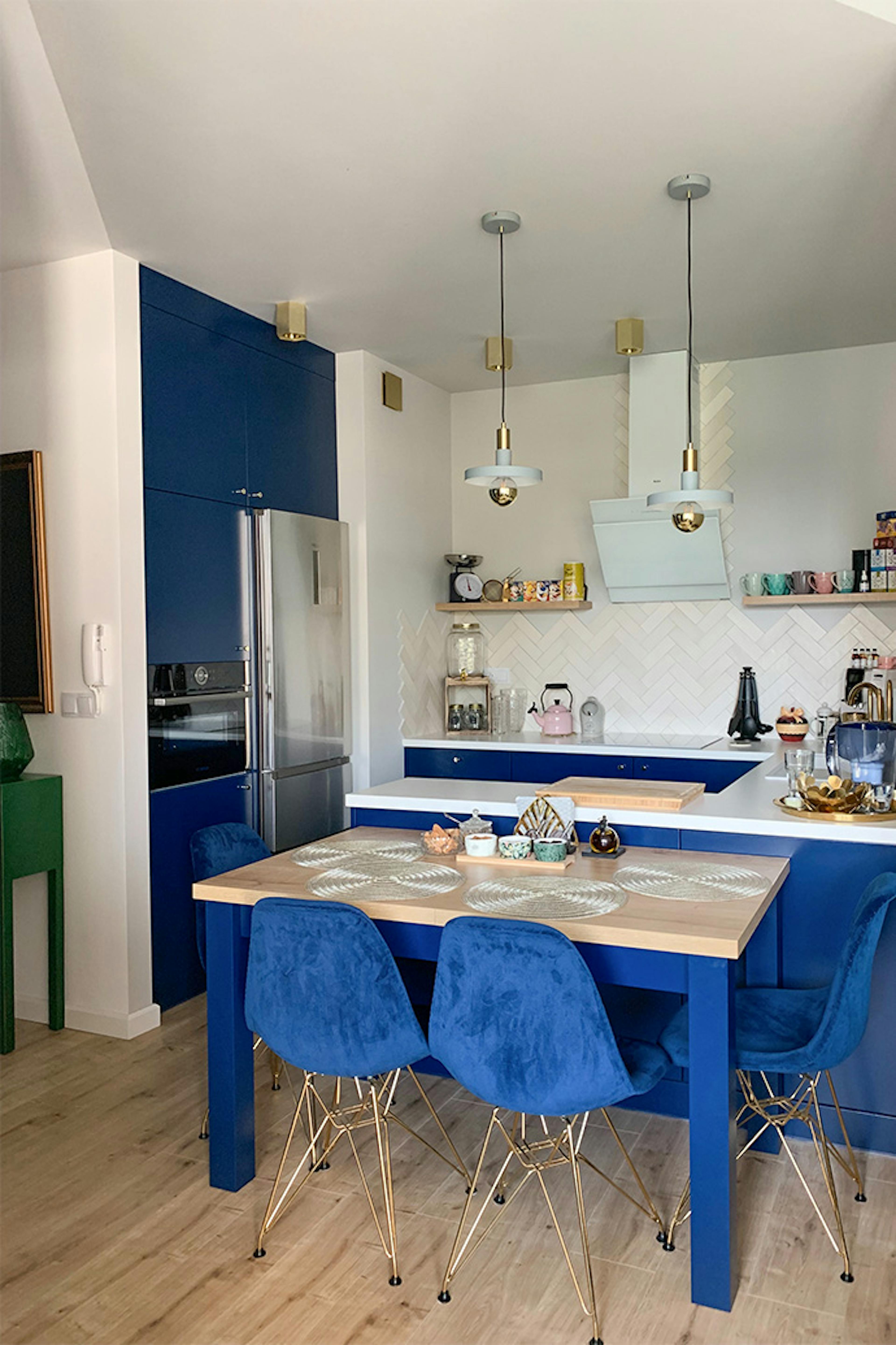 Moderne Küche, blaue Möbel für die Küche, goldene Accessoires in der Küche, blaue Stühle im Esszimmer, Hängelampen für die Küche