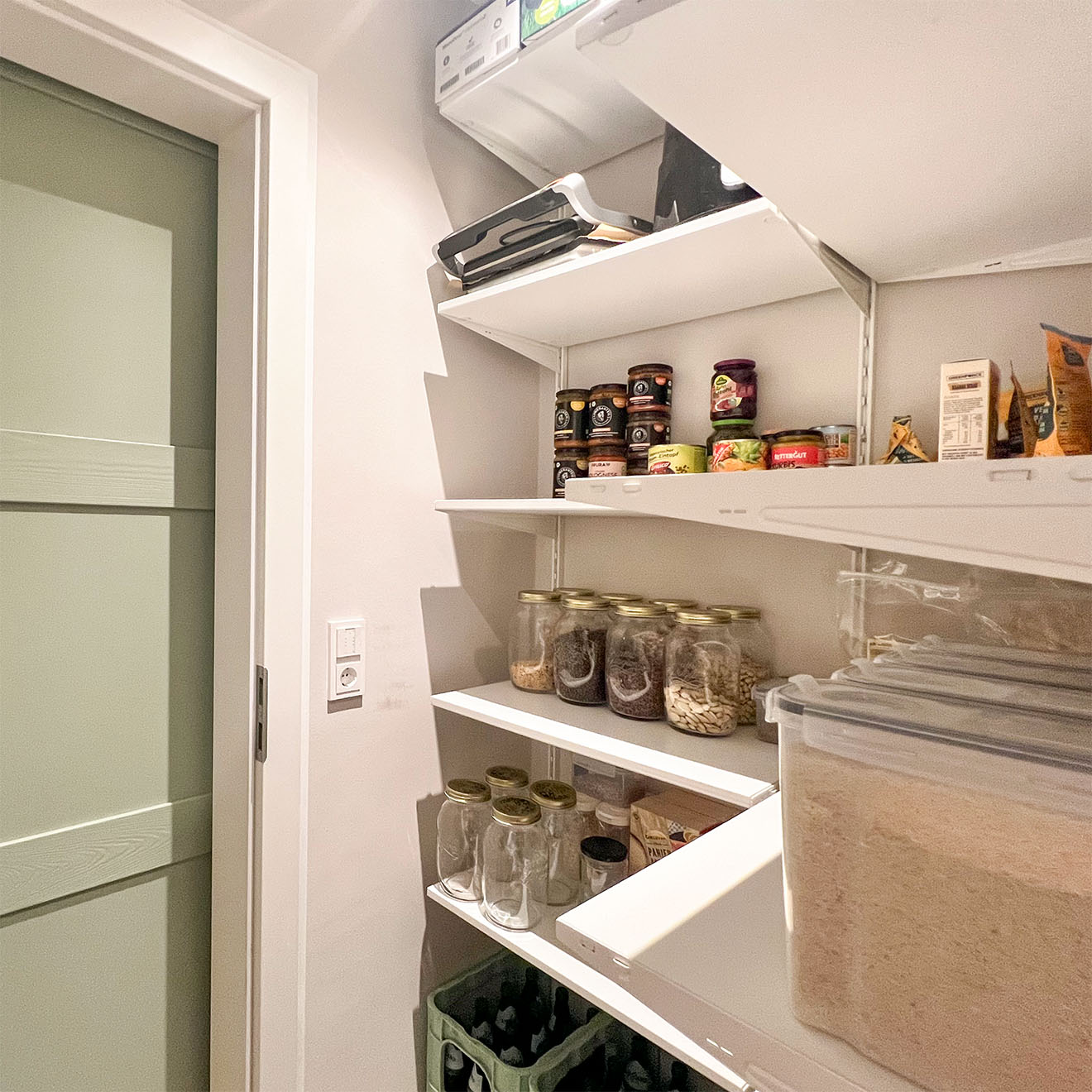 wnętrze spiżarni z artykułami spożywczymi na białych półkach