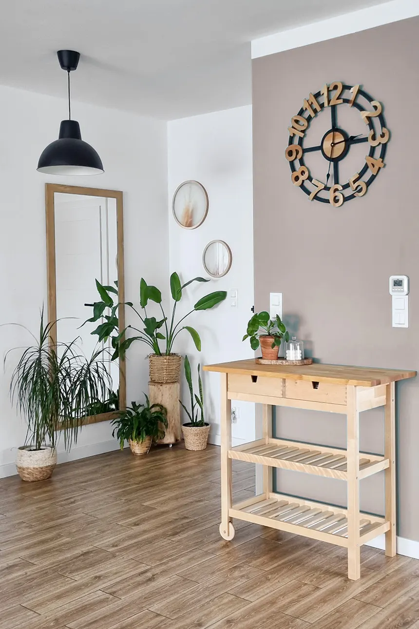 duży designerski zegar na szałwiowej ścianie nad drewnianym regałem w przedpokoju