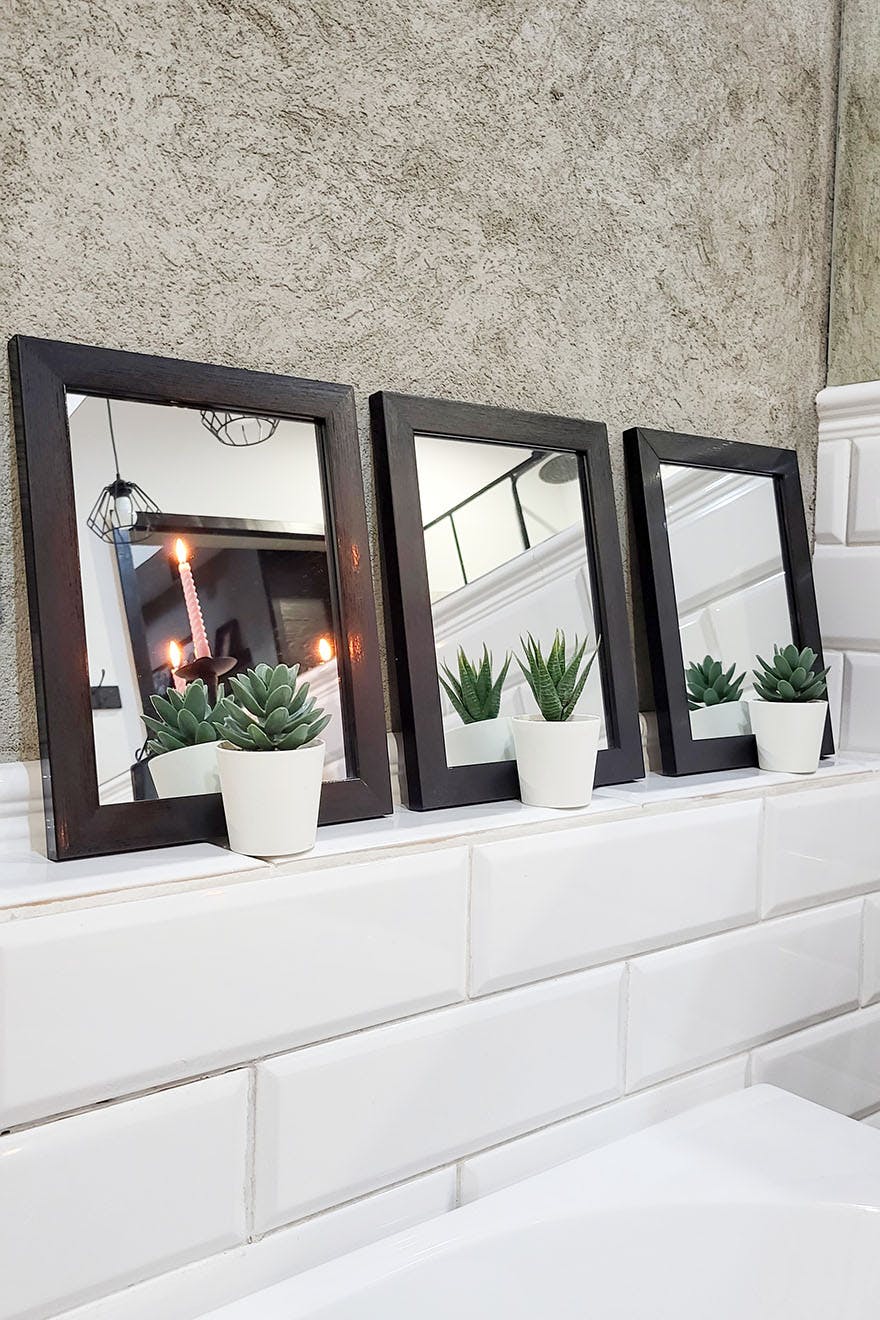 ein Satz kleiner Spiegel mit quadratischem Rahmen über der Badewanne im Badezimmer