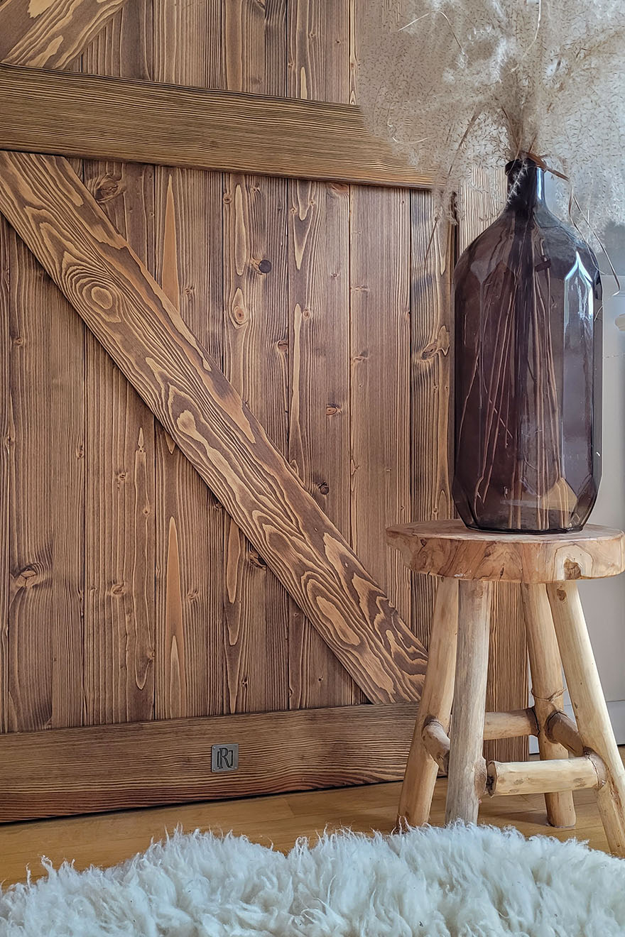 Vase auf einem Holzhocker neben einer Massivholztür