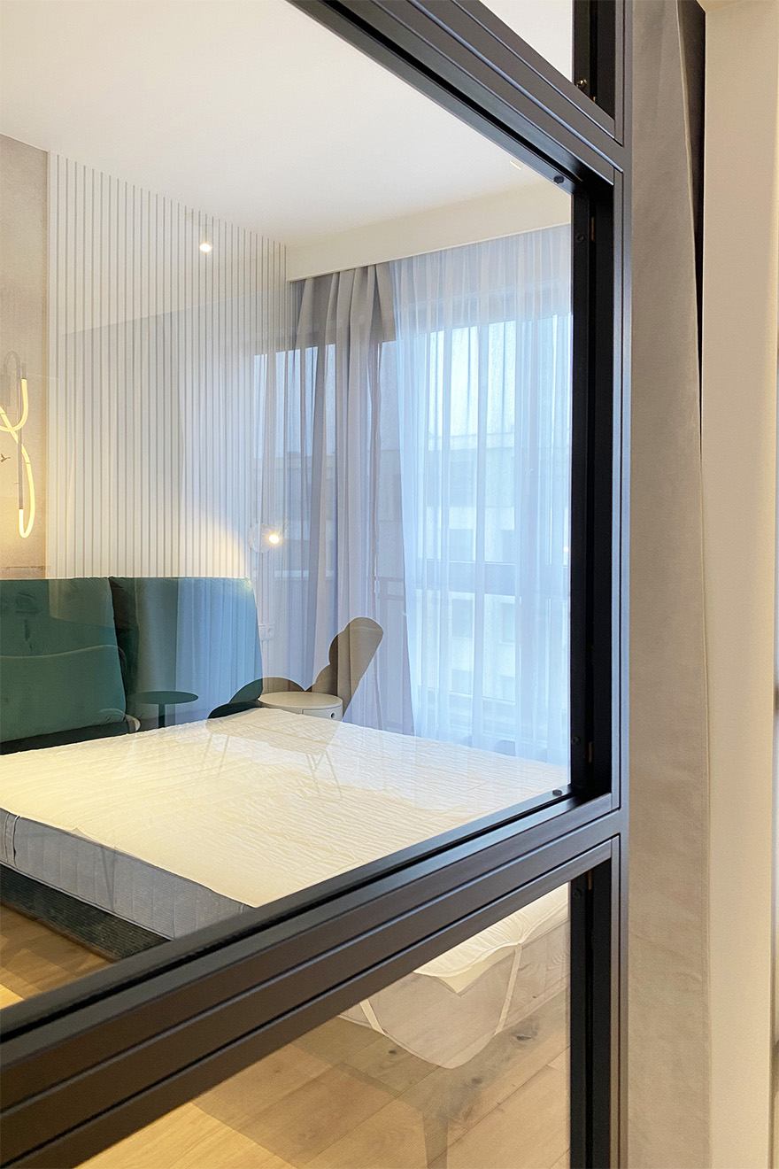 Glasschiebetüren, schwarzer Metallrahmen mit Glas gefüllt, der das Schlafzimmer vom Wohnzimmer trennt, moderne Wohnung