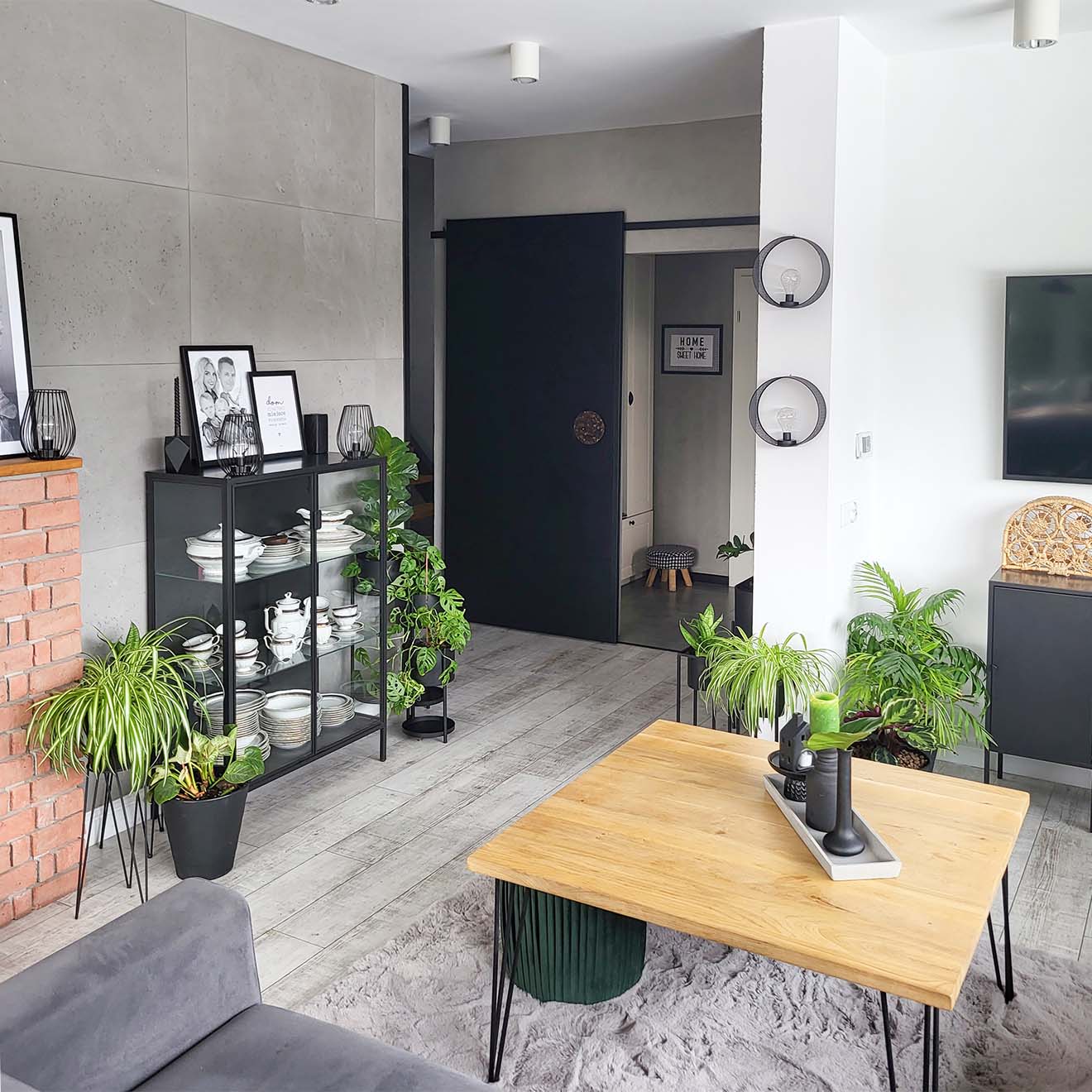 ein holztisch auf metallbeinen, eine schwarze glasvitrine und schwarze schiebetüren in einem modernen wohnzimmer