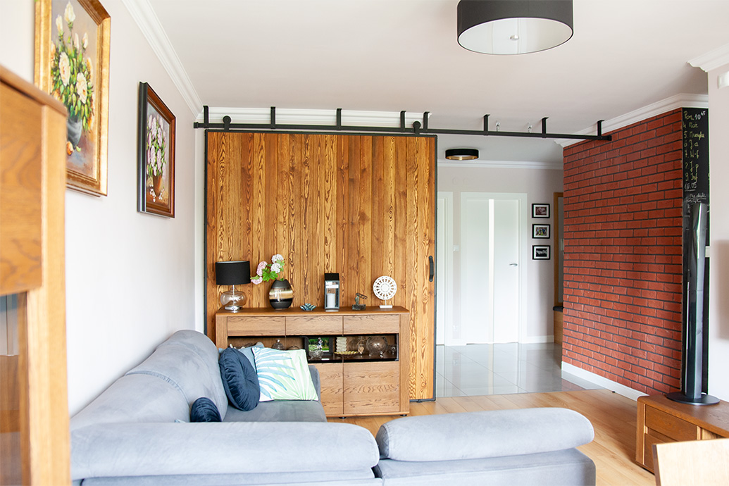 große Schiebetür in einem Metallrahmen, Ziegel an der Wand, Schiebewand im Wohnzimmer, graues Sofa