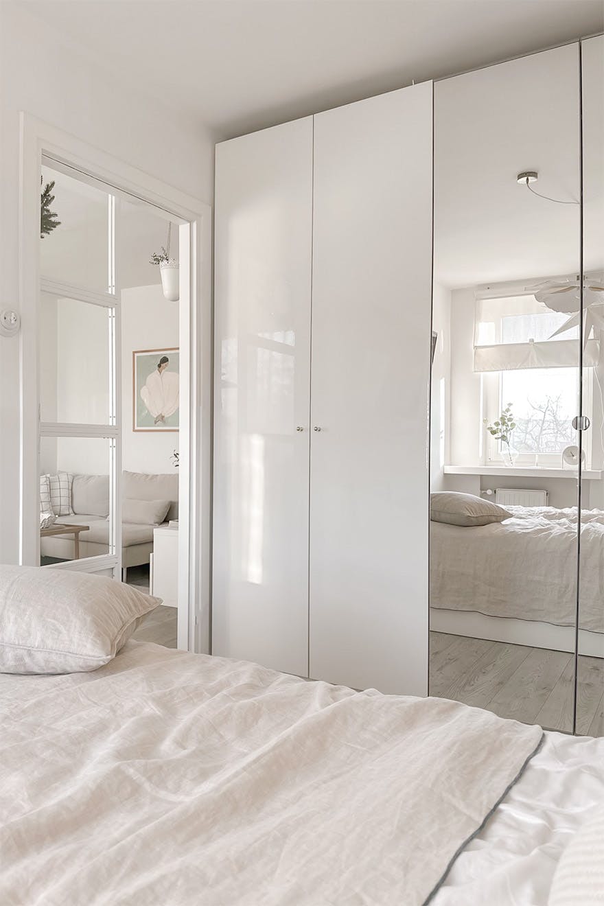 Weißer Kleiderschrank mit Spiegel in einem hellen Schlafzimmer