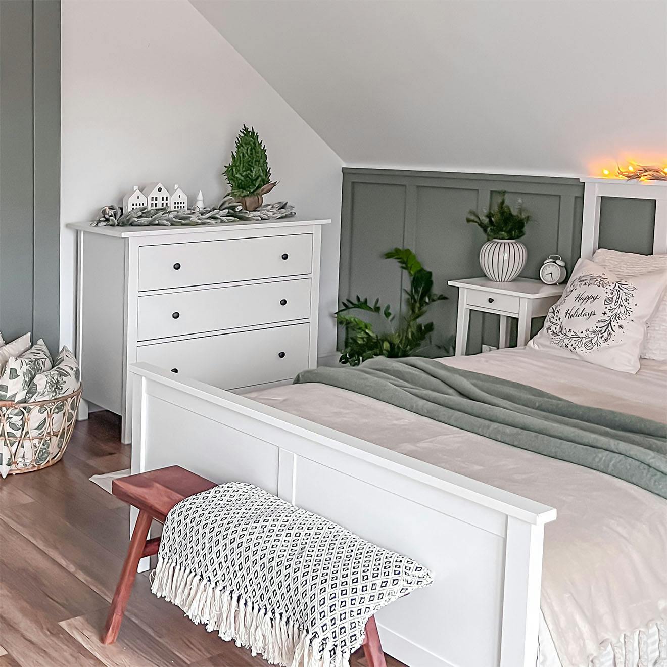 białe łóżko i biała komoda ustawione pod skośnym sufitem w sypialni