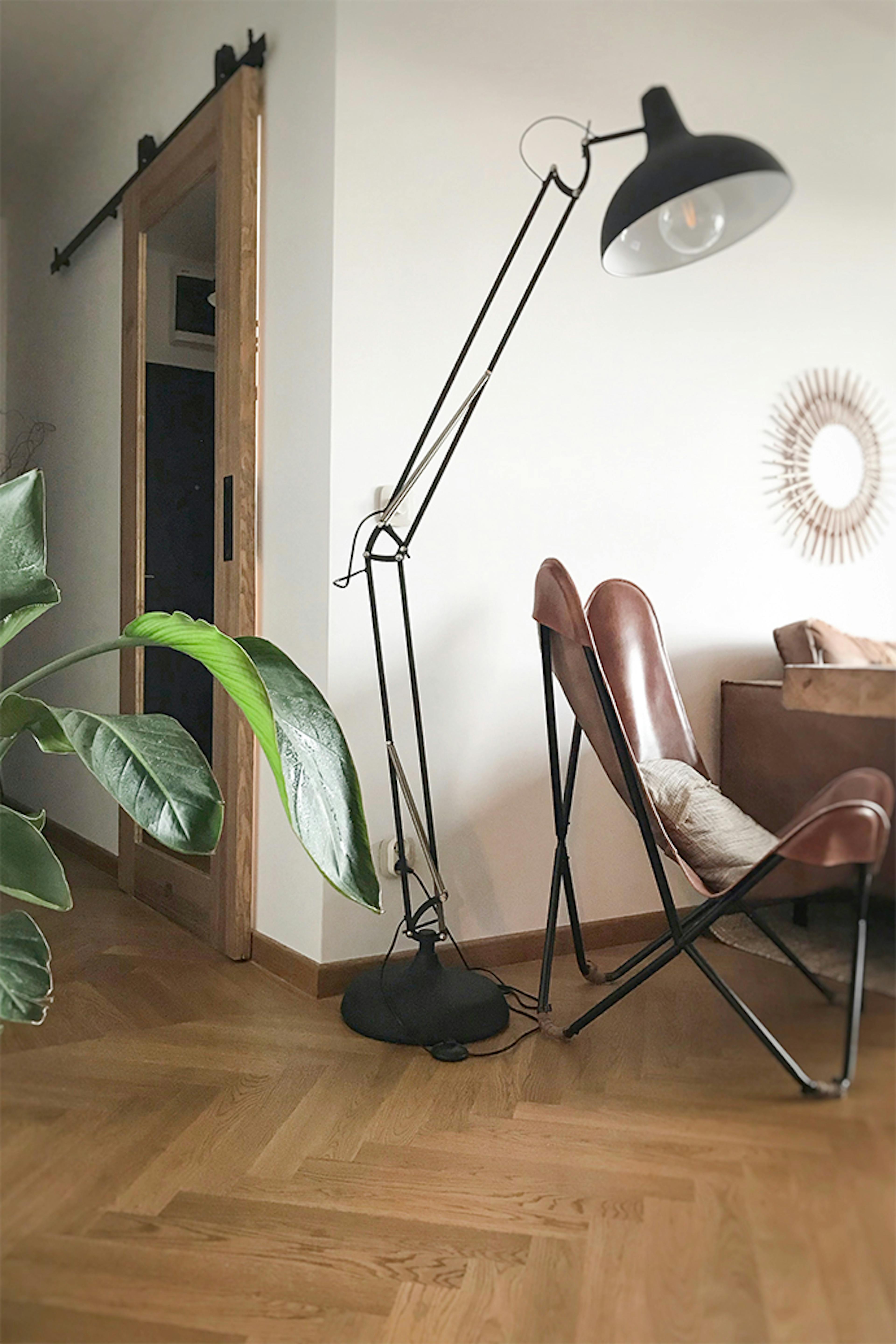Schiebetür zum Büro, Holztür mit Spiegel, Schiebetür mit Spiegel, große Stehlampe aus Metall, Ledersessel auf Metallbasis, Vintage-Sessel, Parkettboden im Wohnzimmer, Spiegel im Flur