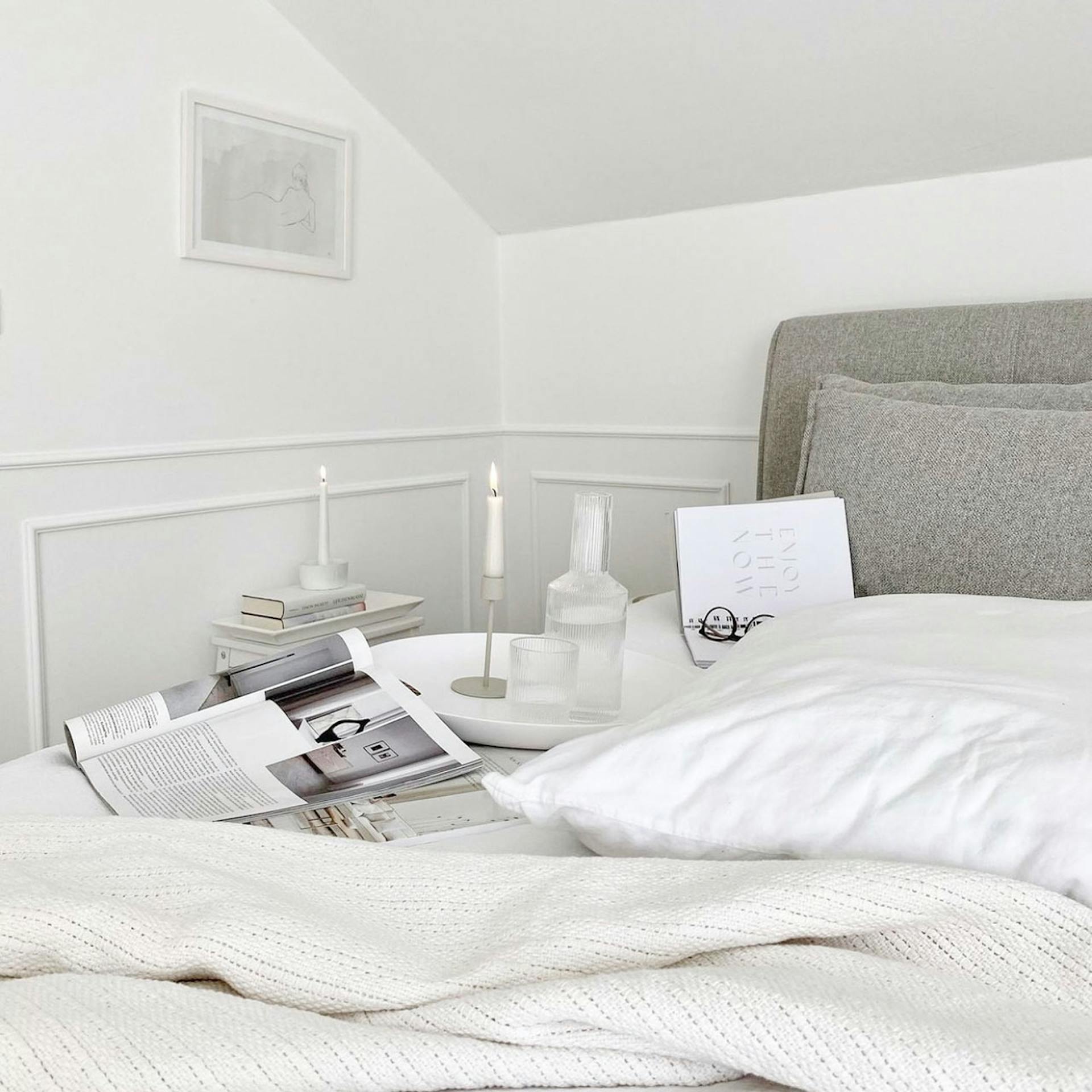 Weiße Bettwäsche auf einem Bett mit gepolstertem Kopfteil