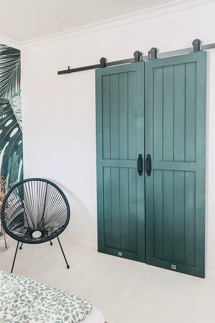 Schwarzer durchbrochener Stuhl neben grünen Doppelschiebetüren