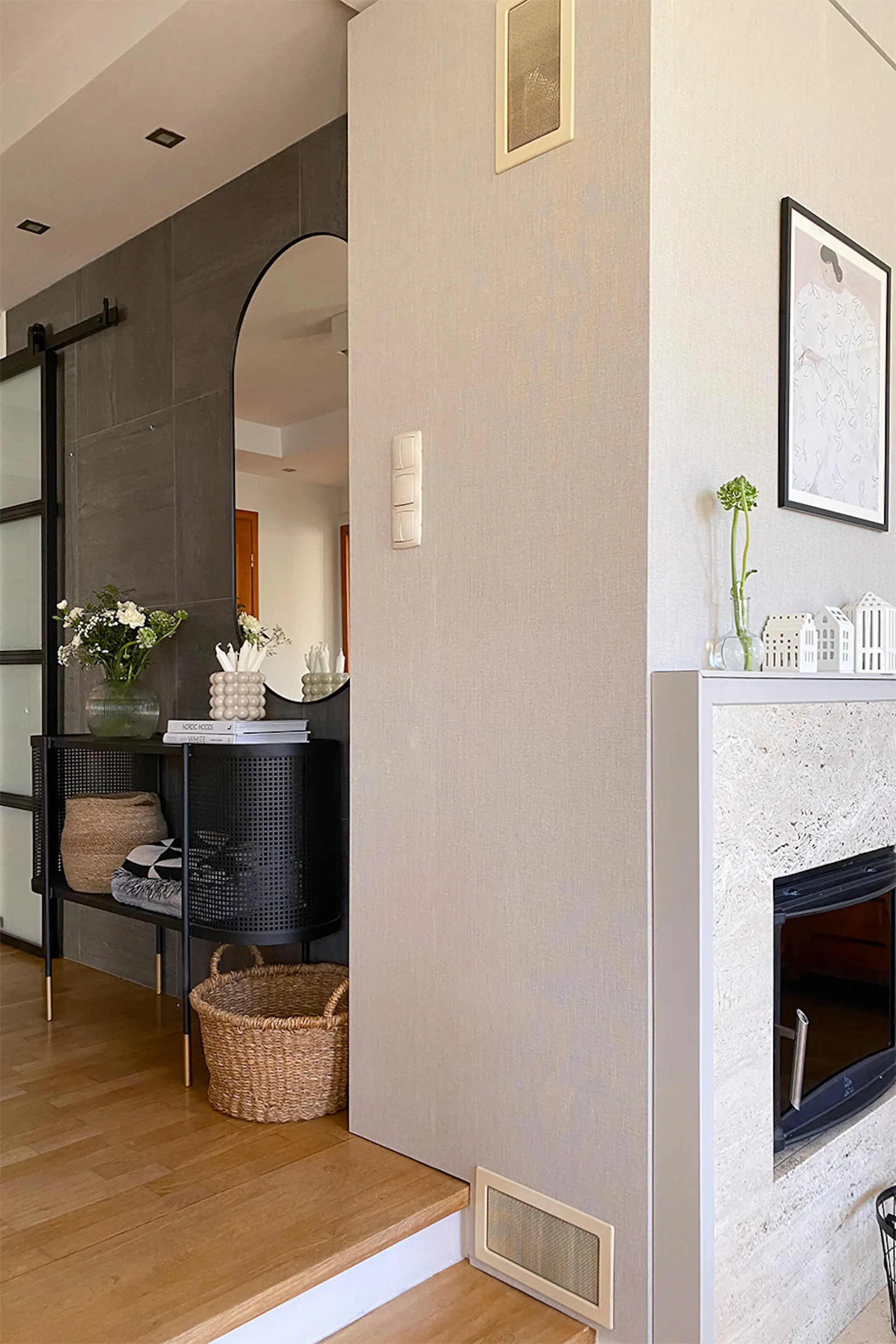 Creme- und Grautöne im Durchgang zwischen Wohnzimmer und Diele, schwarze durchbrochene Konsole in der Diele, Spiegel über der Konsole, Weidenkorb