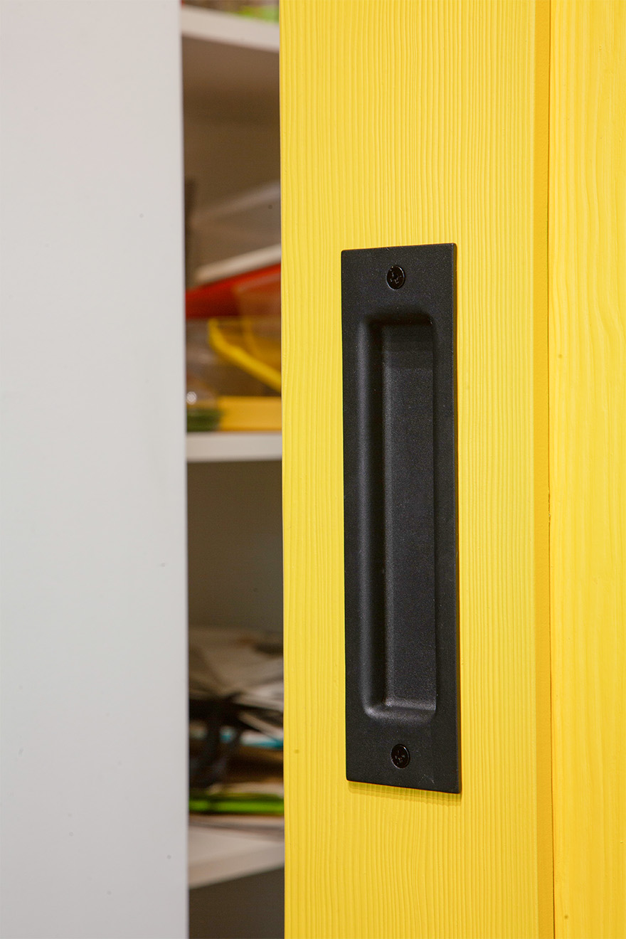 czarna klamka na żółtych drzwiach drewnianych