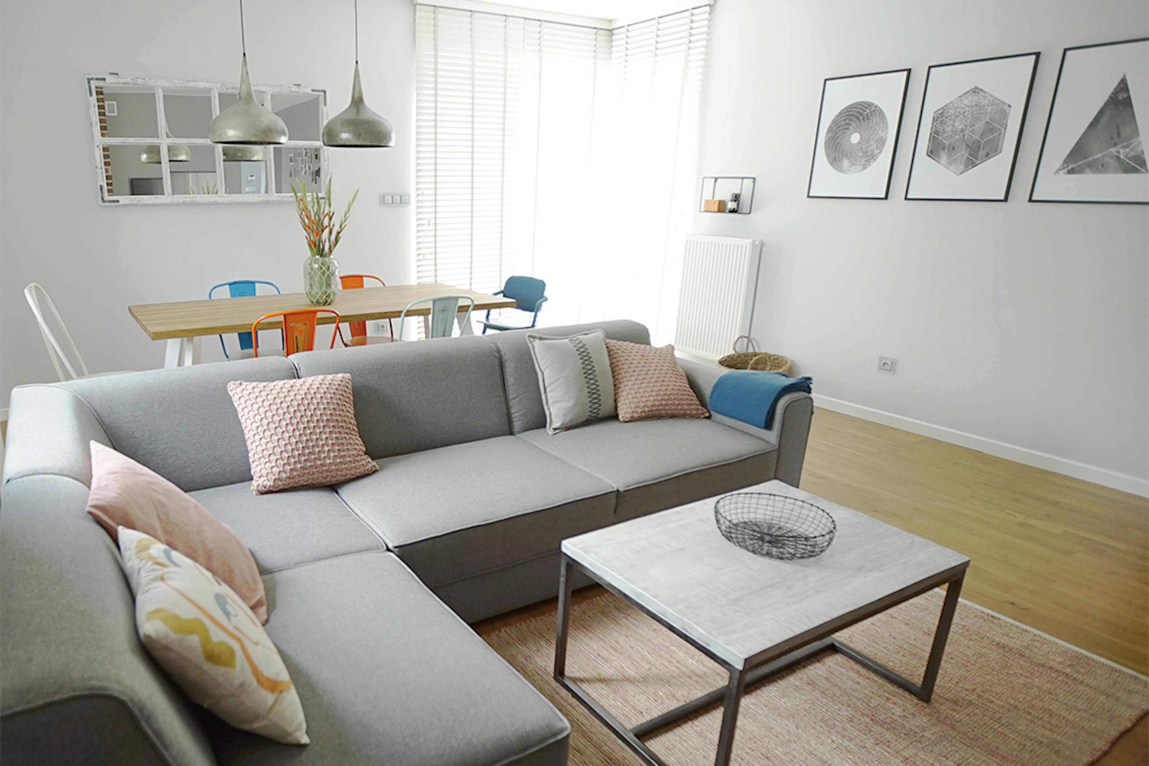 Wohnzimmer Anordnung, graues Sofa im Wohnzimmer, bunte Accessoires im Wohnzimmer, Wanddekorationen