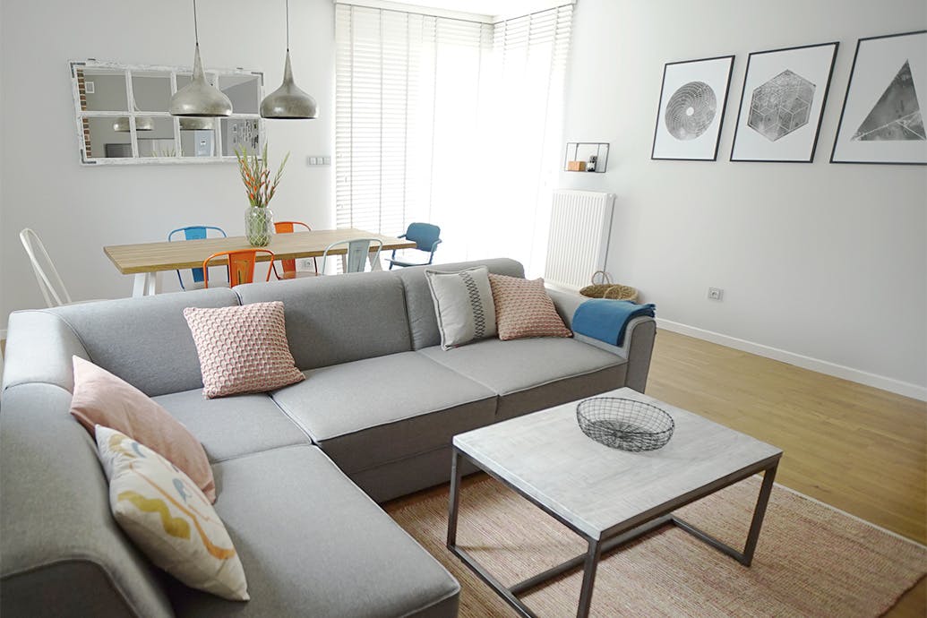 Wohnzimmer Anordnung, graues Sofa im Wohnzimmer, bunte Accessoires im Wohnzimmer, Wanddekorationen