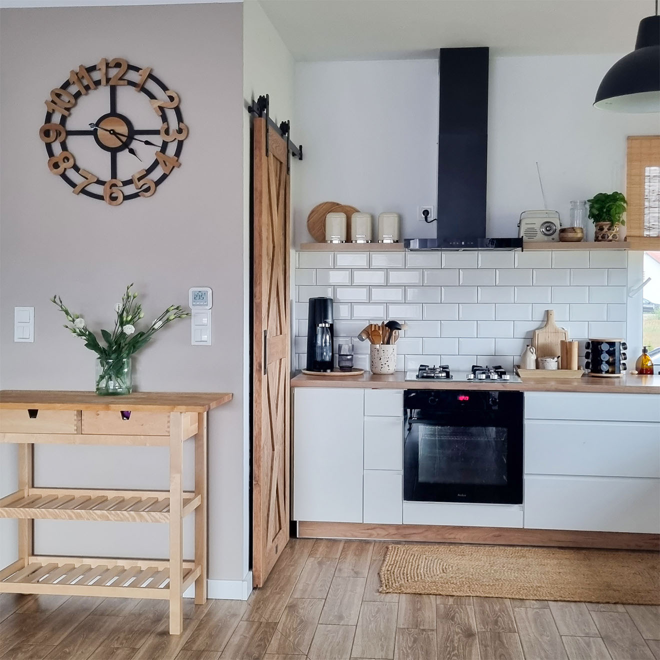 weiße Küchenschränke mit Holzplatte neben der Holztür zur Speisekammer