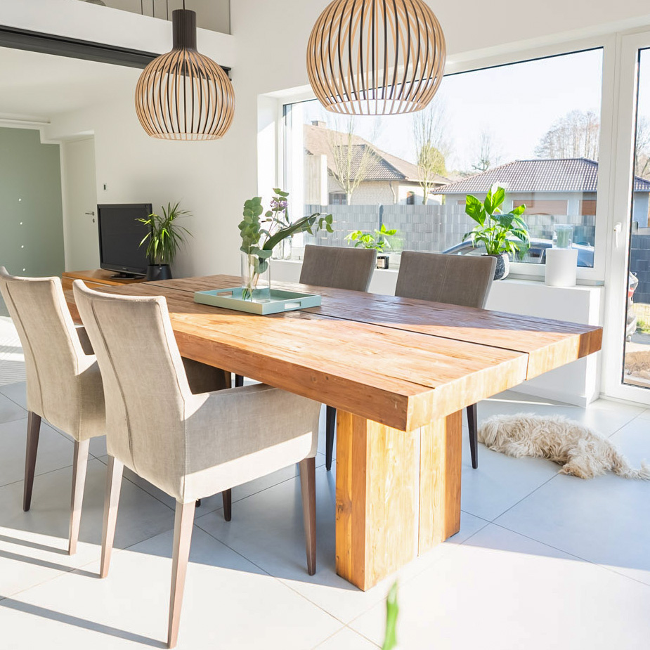 Massivholz-Esstisch, beige Polsterstühle, durchbrochene Hängelampen über dem Esstisch, modernes Wohnzimmer