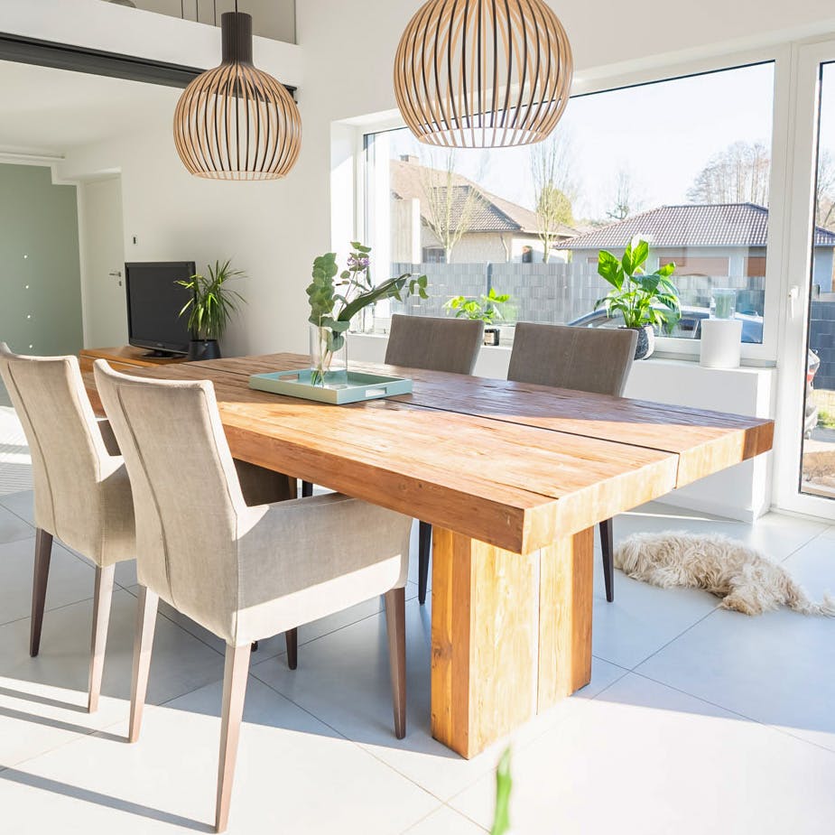 Massivholz-Esstisch, beige Polsterstühle, durchbrochene Hängelampen über dem Esstisch, modernes Wohnzimmer