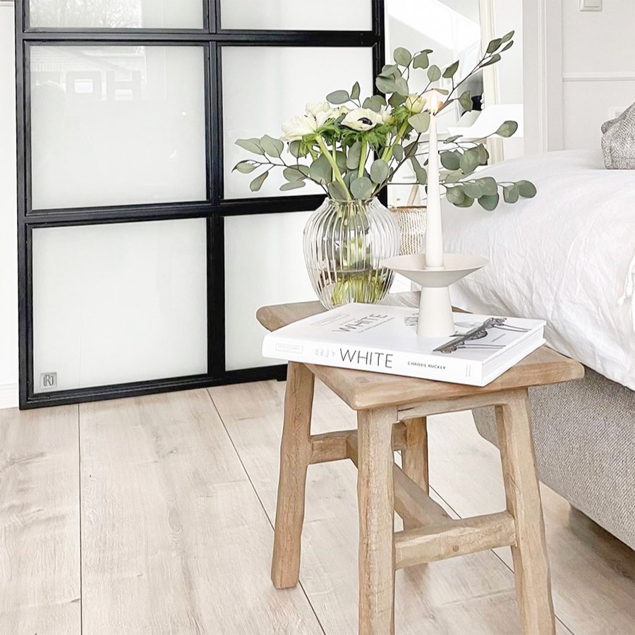 Holztisch neben dem Bett in einem Schlafzimmer im Nordic Stil