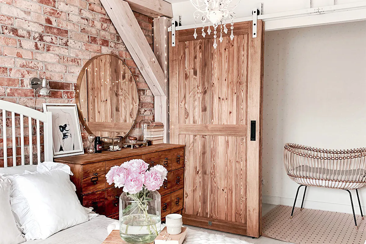 drzwi przesuwne drewniane, drzwi przesuwne naprzemienne, styl rustykalny we wnętrzach, styl modern rustic, drzwi w stylu „barn door”, biały system przesuwny, system przesuwny do drzwi naprzemiennych, cegła na ścianie w sypialni,, rustykalna komoda w sypialni,