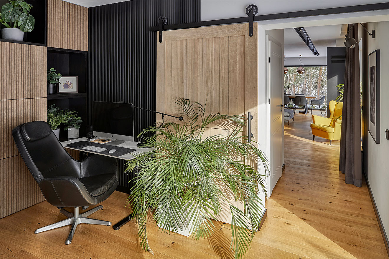 domowe biuro z małym biurkiem, skórzanym fotelem i drewnianymi drzwiami przesuwnymi