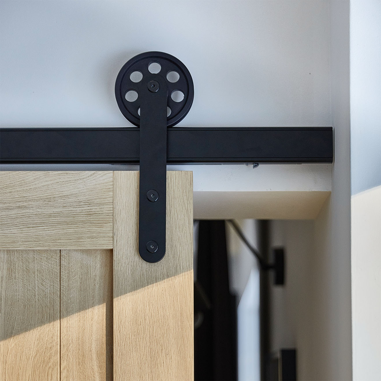 czarny system przesuwny z dużymi rolkami na drewnianych drzwiach