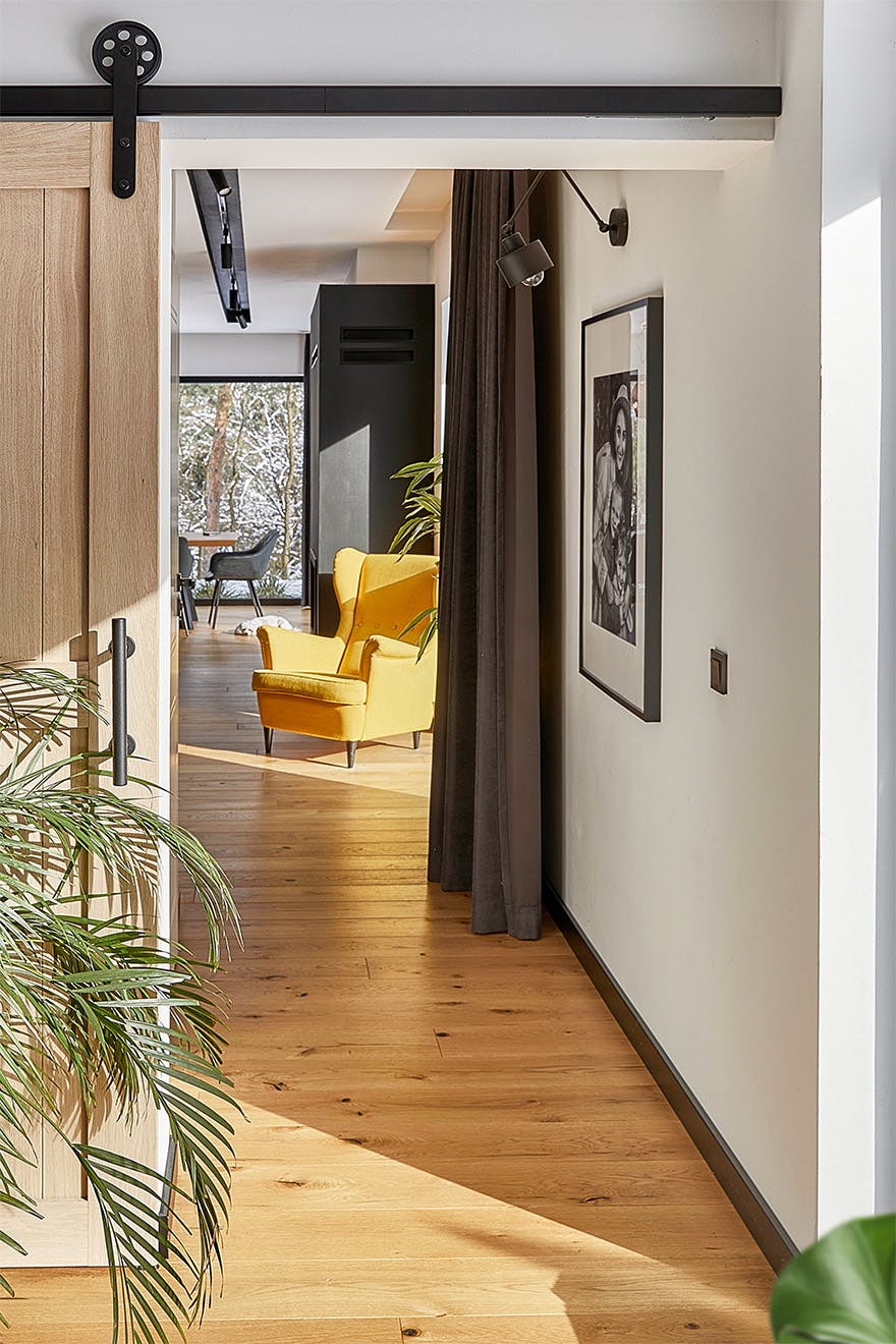 Blick auf den Flur und einen Teil des Wohnzimmers in einem modernen Haus mit Holzböden und schwarzen Akzenten