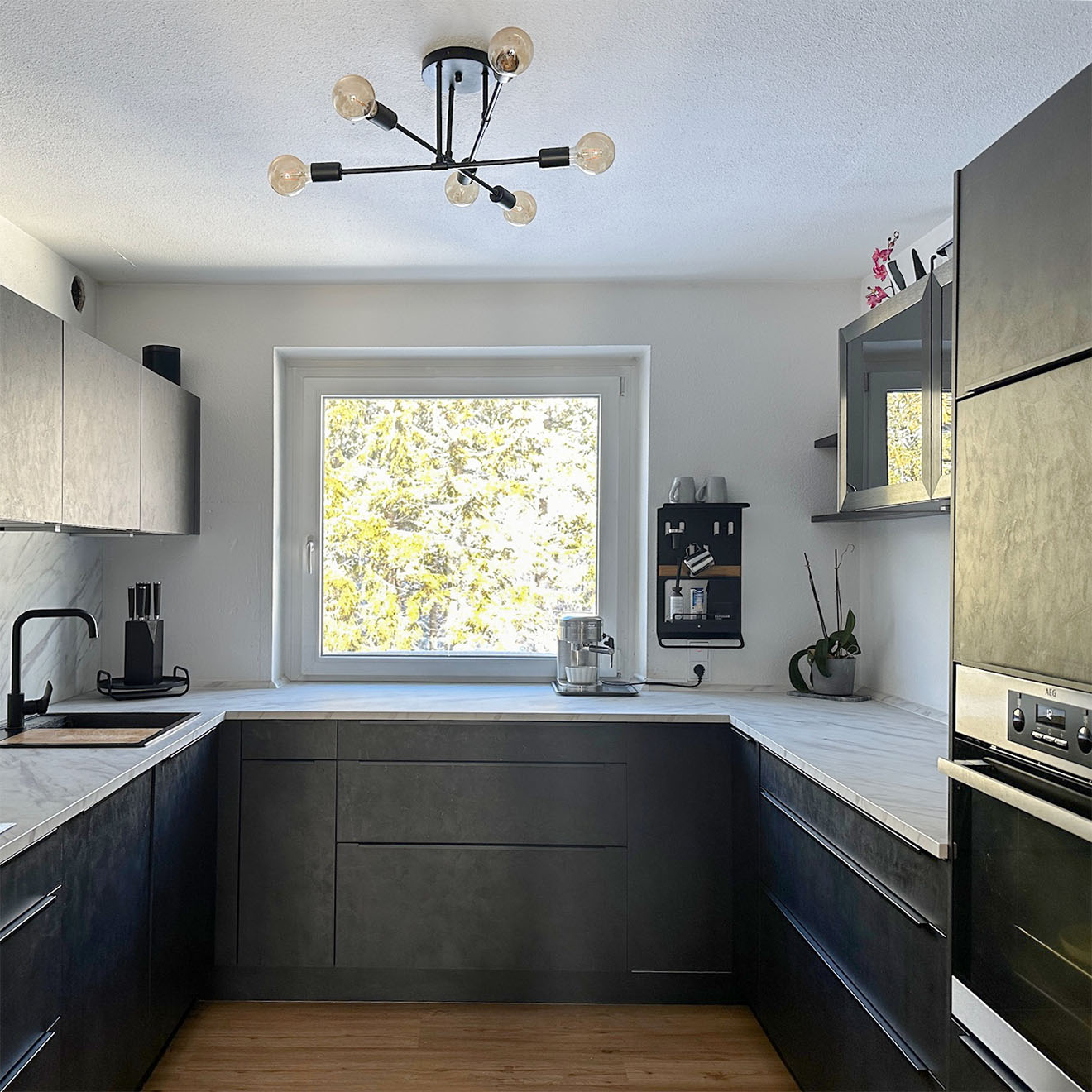 współczesna, minimalistyczna kuchnia z czarnymi szafkami, białymi ścianami i dużym oknem
