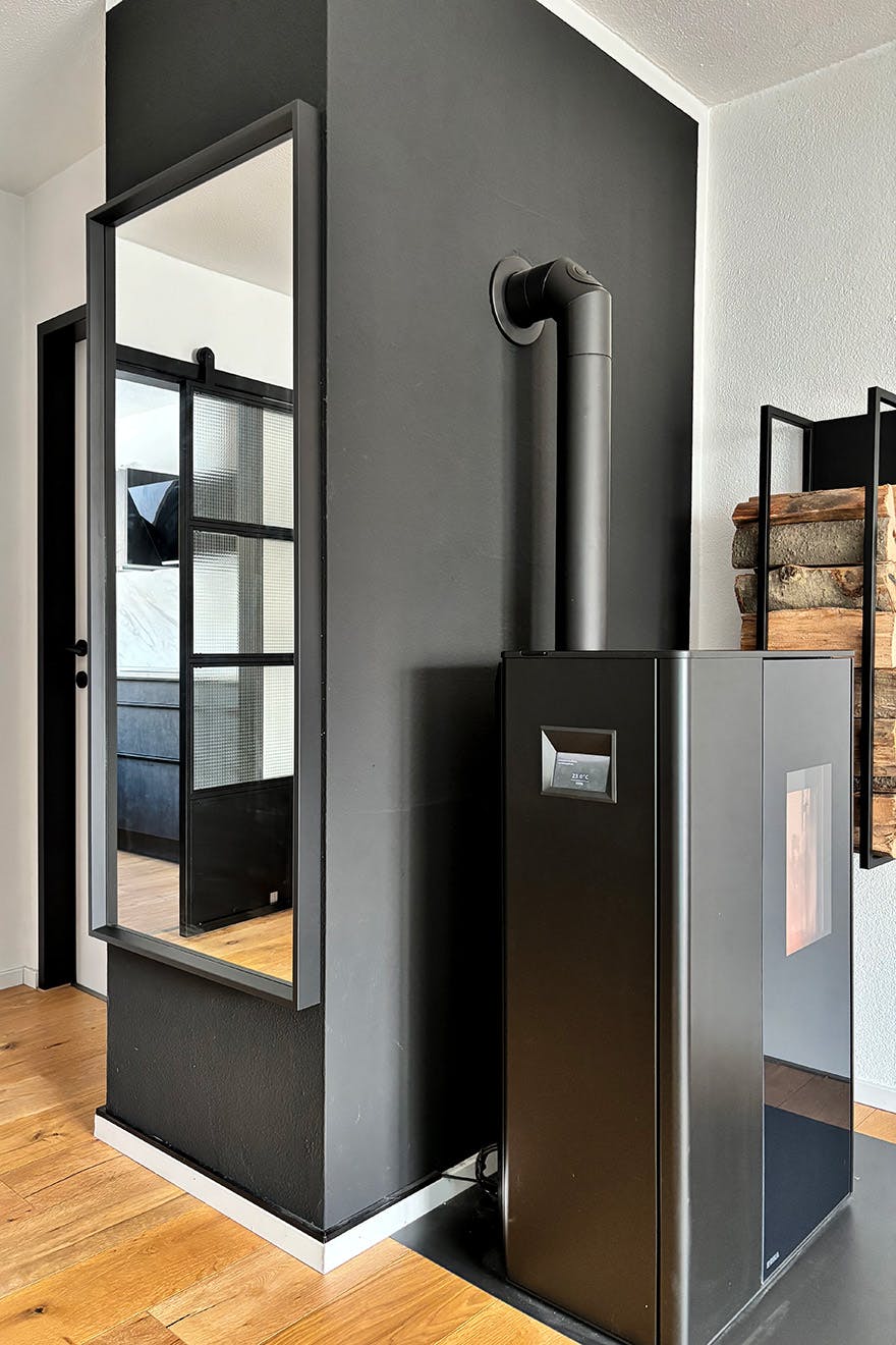 nowoczesny kominek przy czarnej ścianie, na której wisi duże lustro