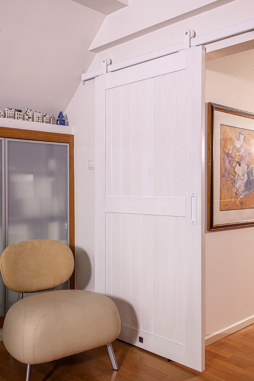 beiger weicher Sessel neben weißen Schiebetüren