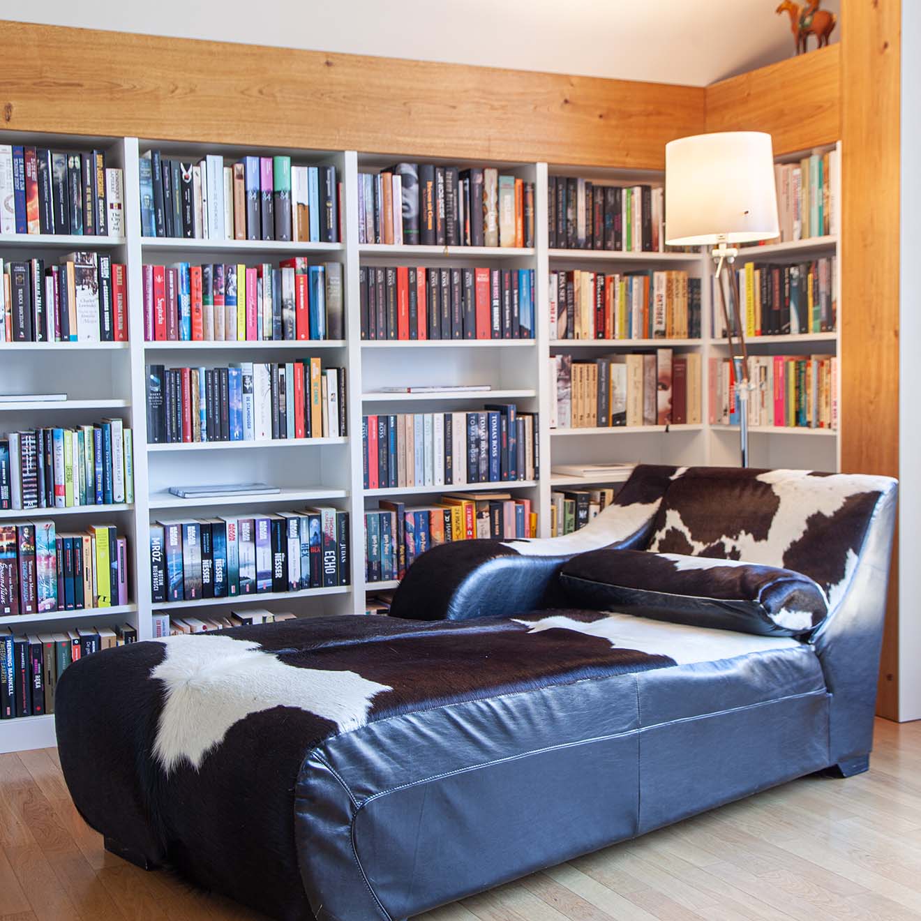 eine Chaiselongue mit schwarz-weißer Polsterung neben einer Wand voller Bücherregale
