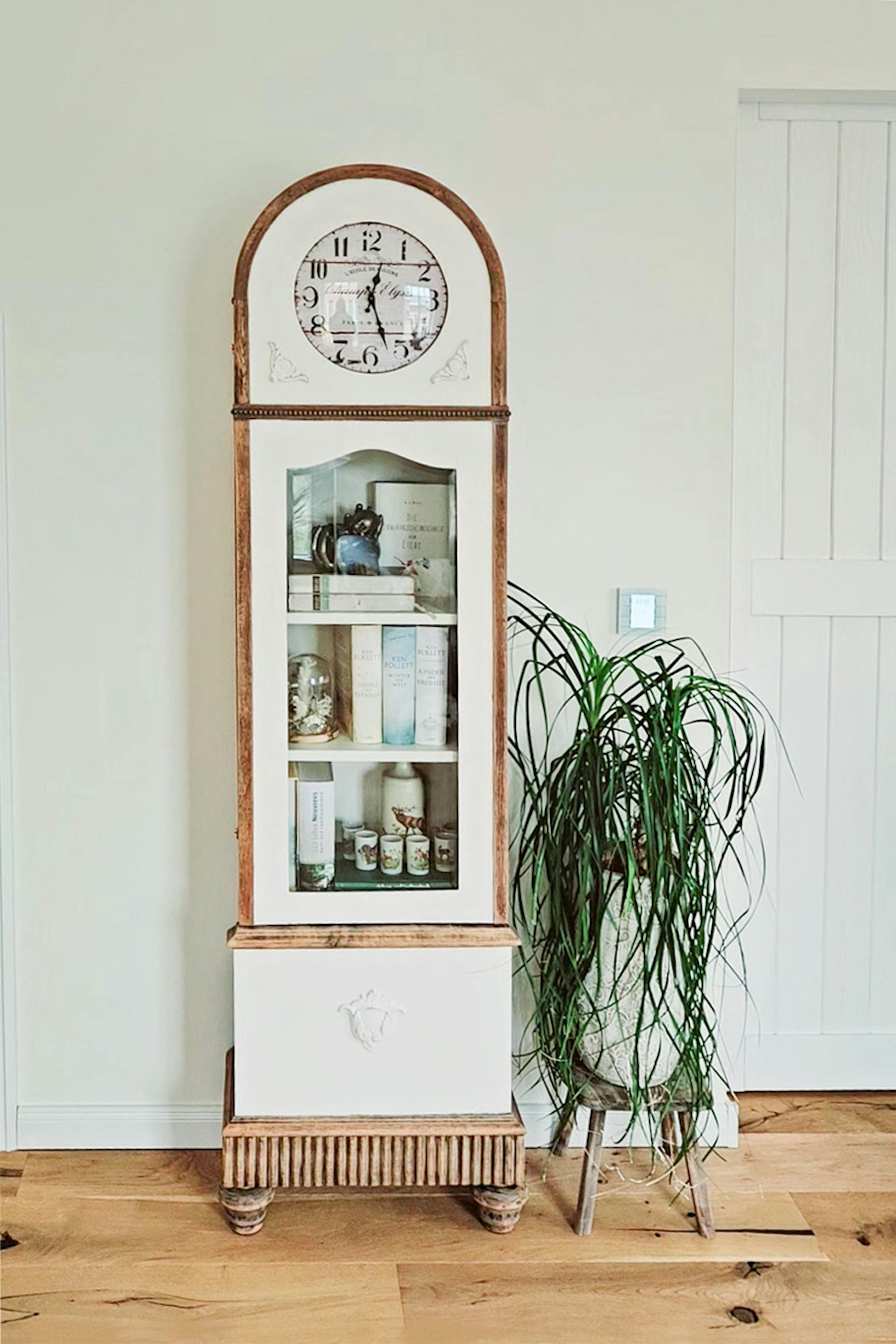 weiße Glasvitrine mit einer Uhr im rustikalen, modernen Stil